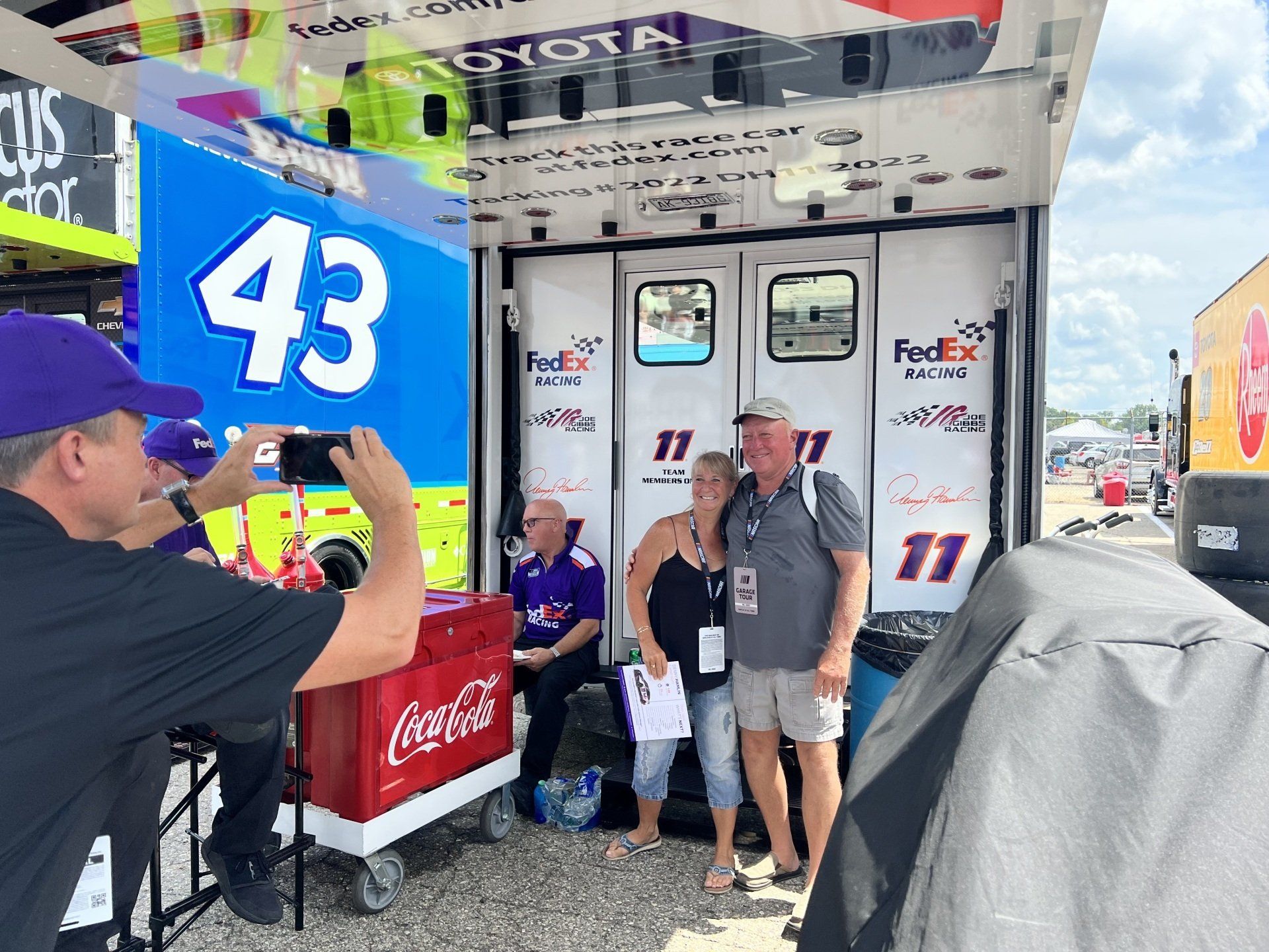 A man is taking a picture of a couple in front of a truck with the number 43 on it
