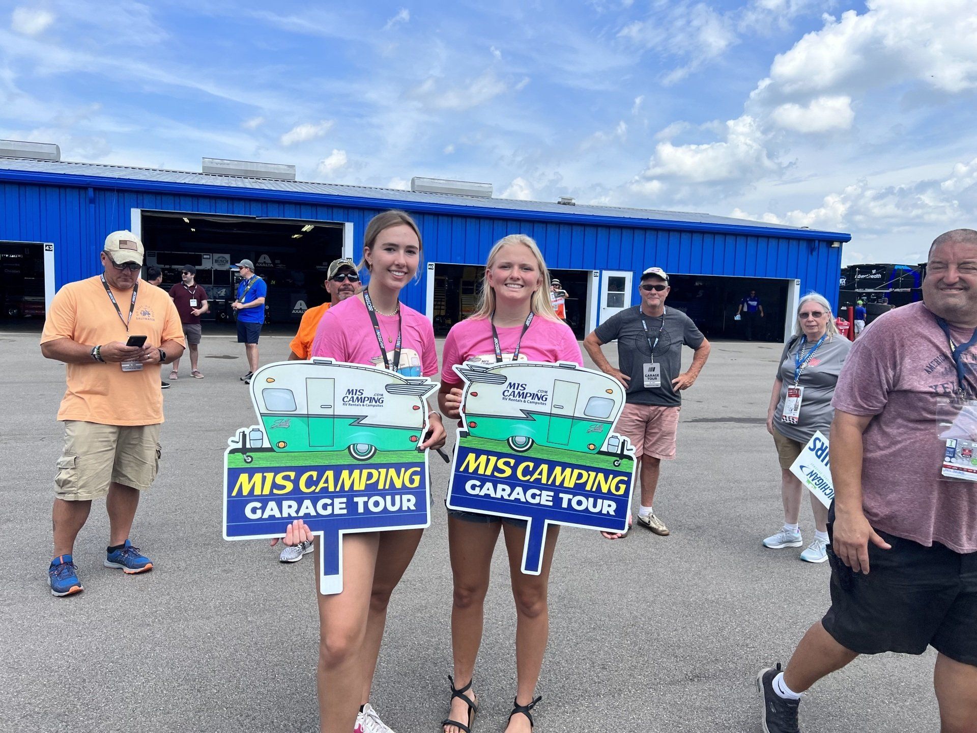 Two women holding signs that say mis camping garage tour