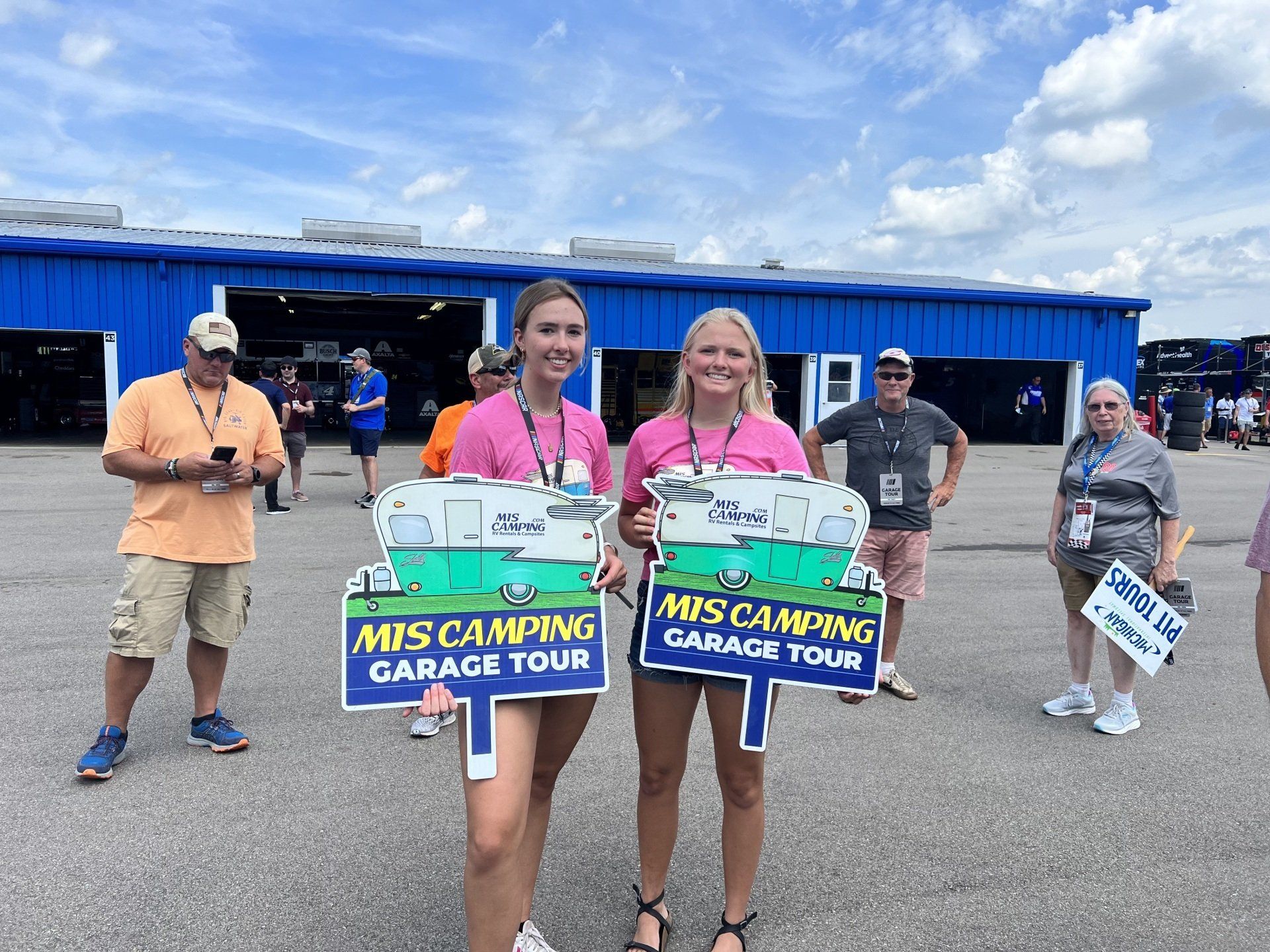 Two girls are holding signs that say mis camping garage tour