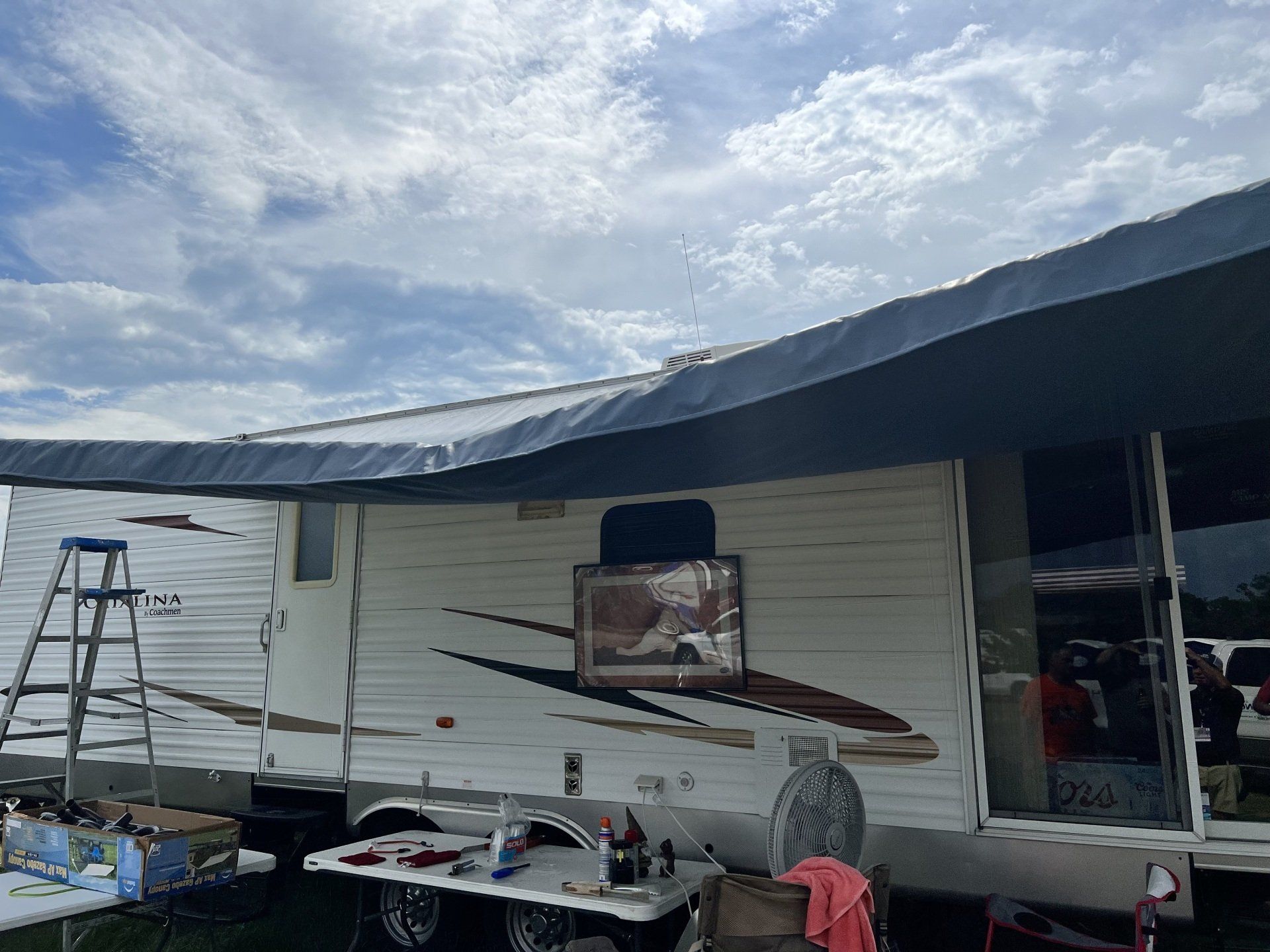 A white rv with a blue awning on top of it.