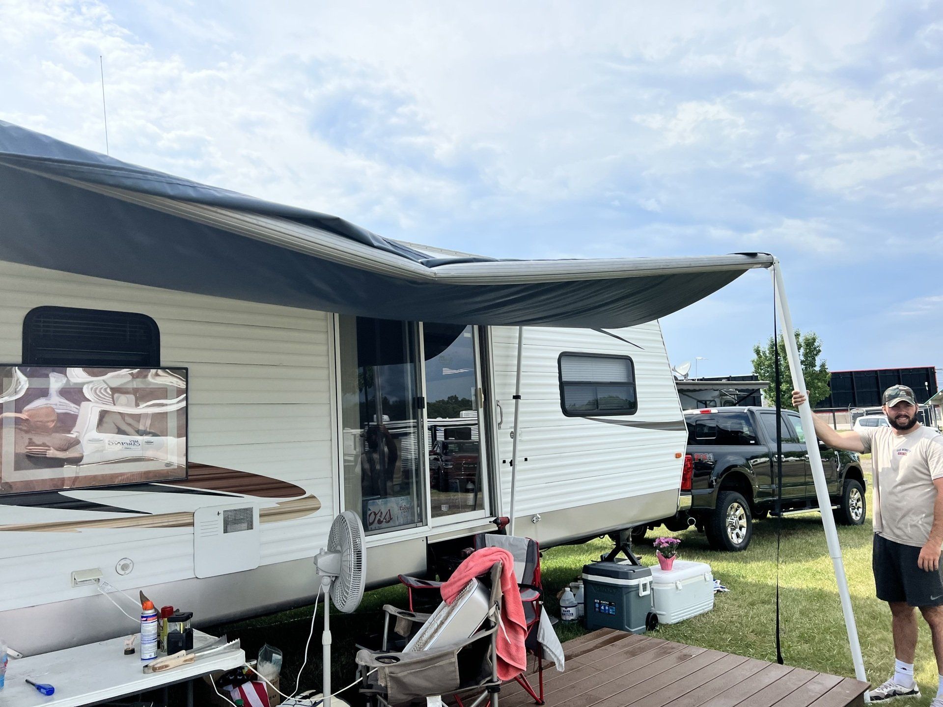 A man is standing in front of a trailer with an awning.