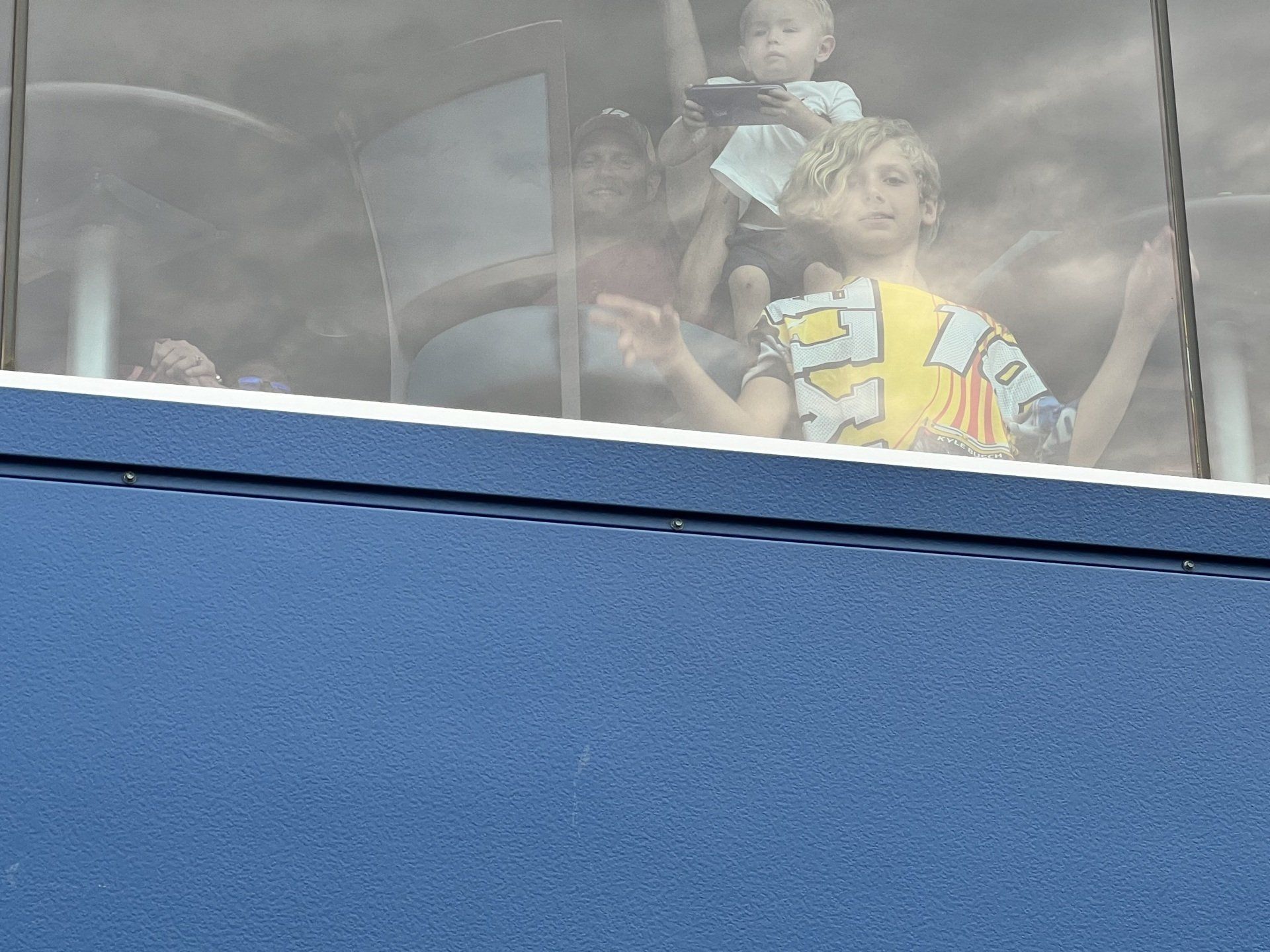 A group of people are looking out of a window and one of them is wearing a shirt with the number 3 on it