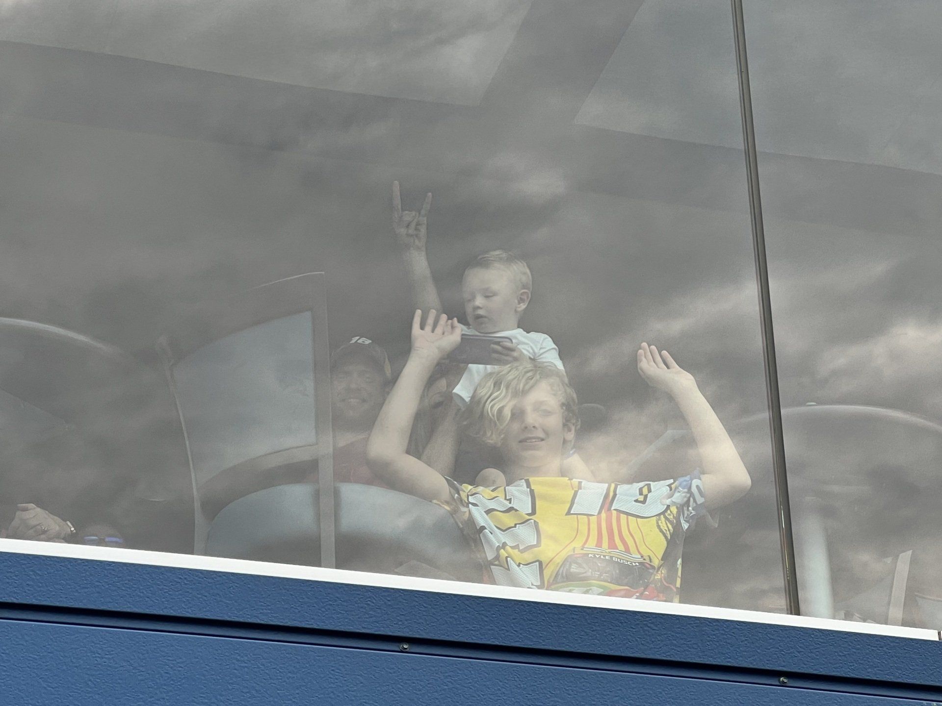 A woman is holding a child on her shoulders while looking out of a window.