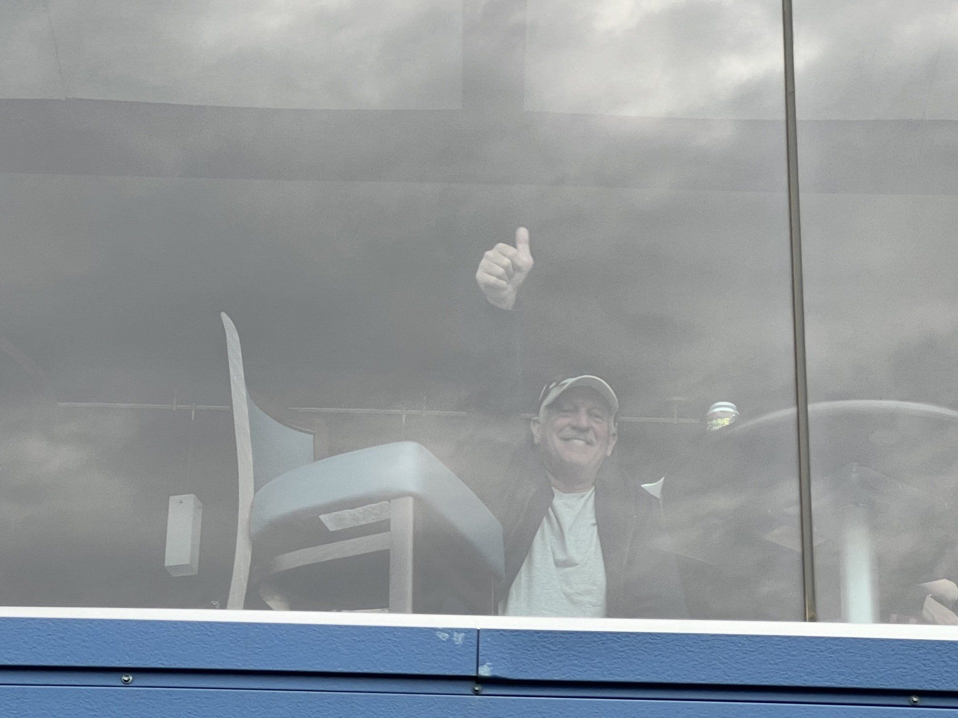 A man is giving a thumbs up while looking out of a window.