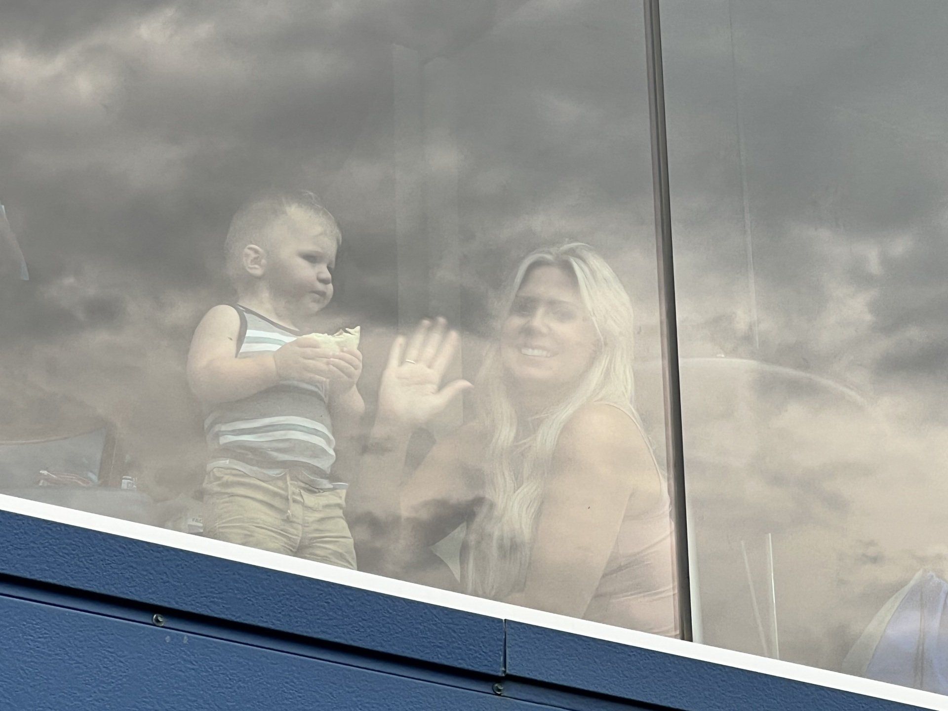 A woman is holding a baby in her arms while looking out a window.