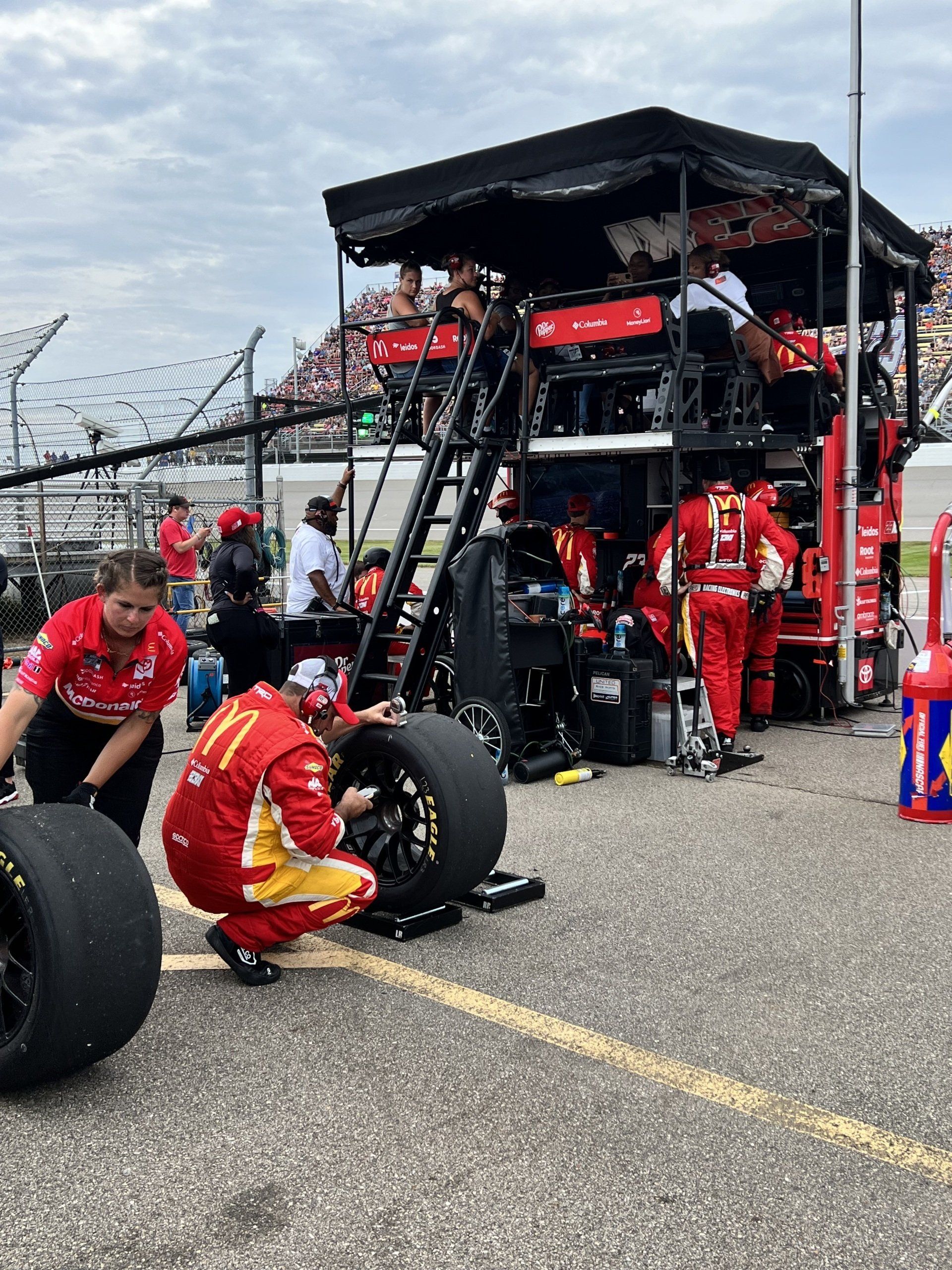 A group of people are working on a race car in a pit lane
