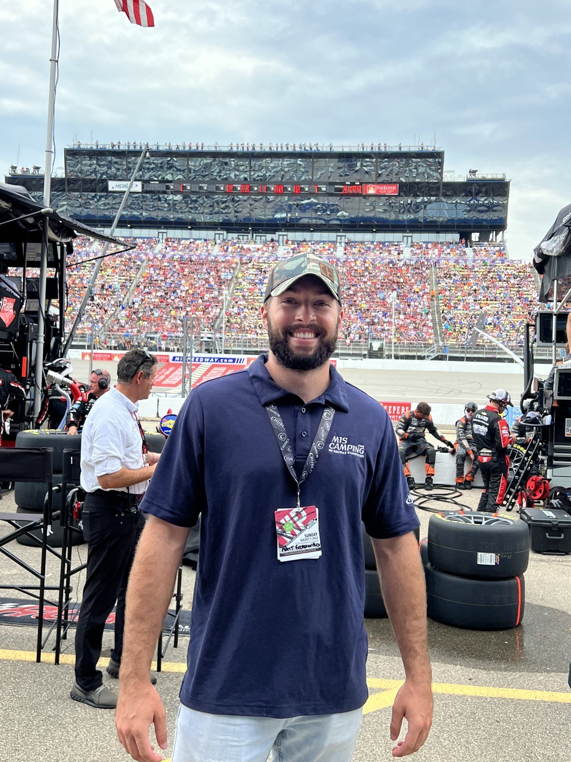 A man with a beard is standing in front of a race track.