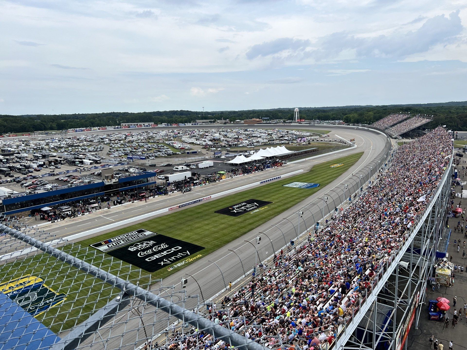 A large crowd of people are watching a race at a race track.