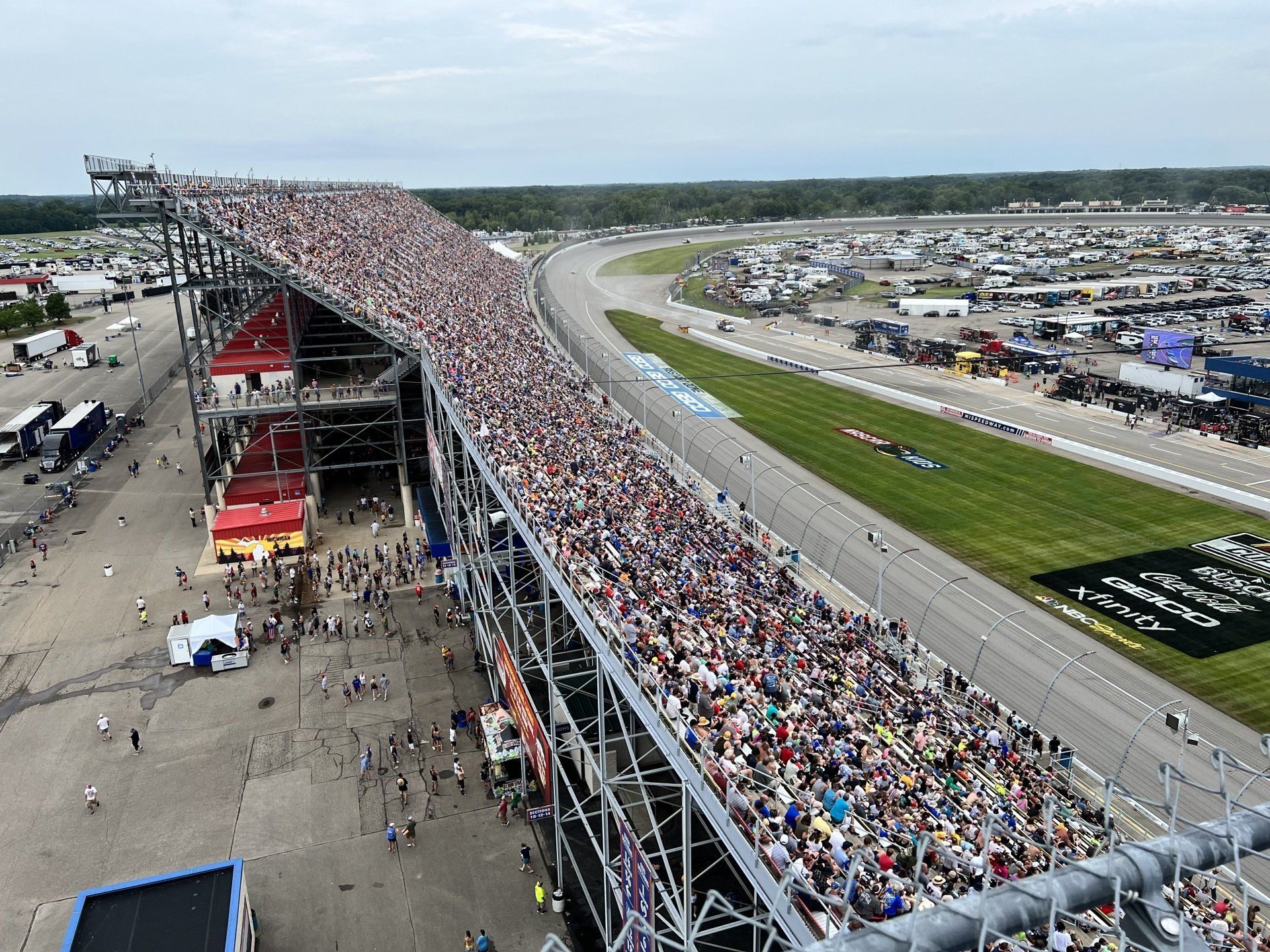 A large crowd of people are watching a race at a race track