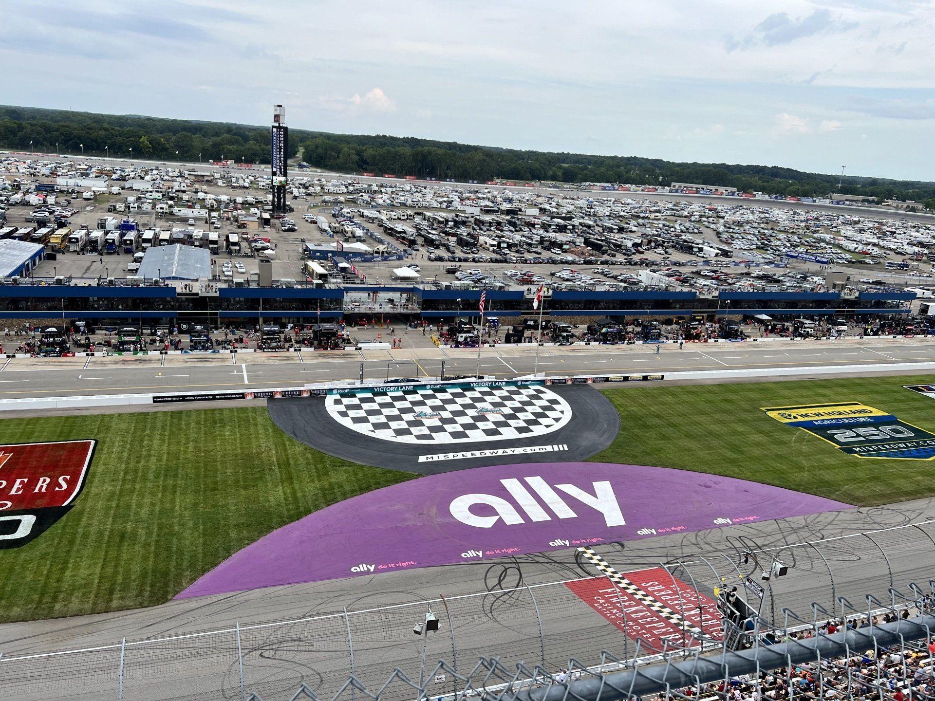 An aerial view of a race track with the word ally painted on the grass