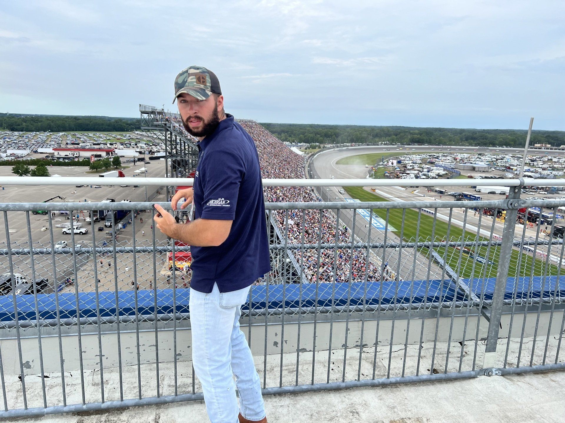 A man is standing on a balcony overlooking a race track.