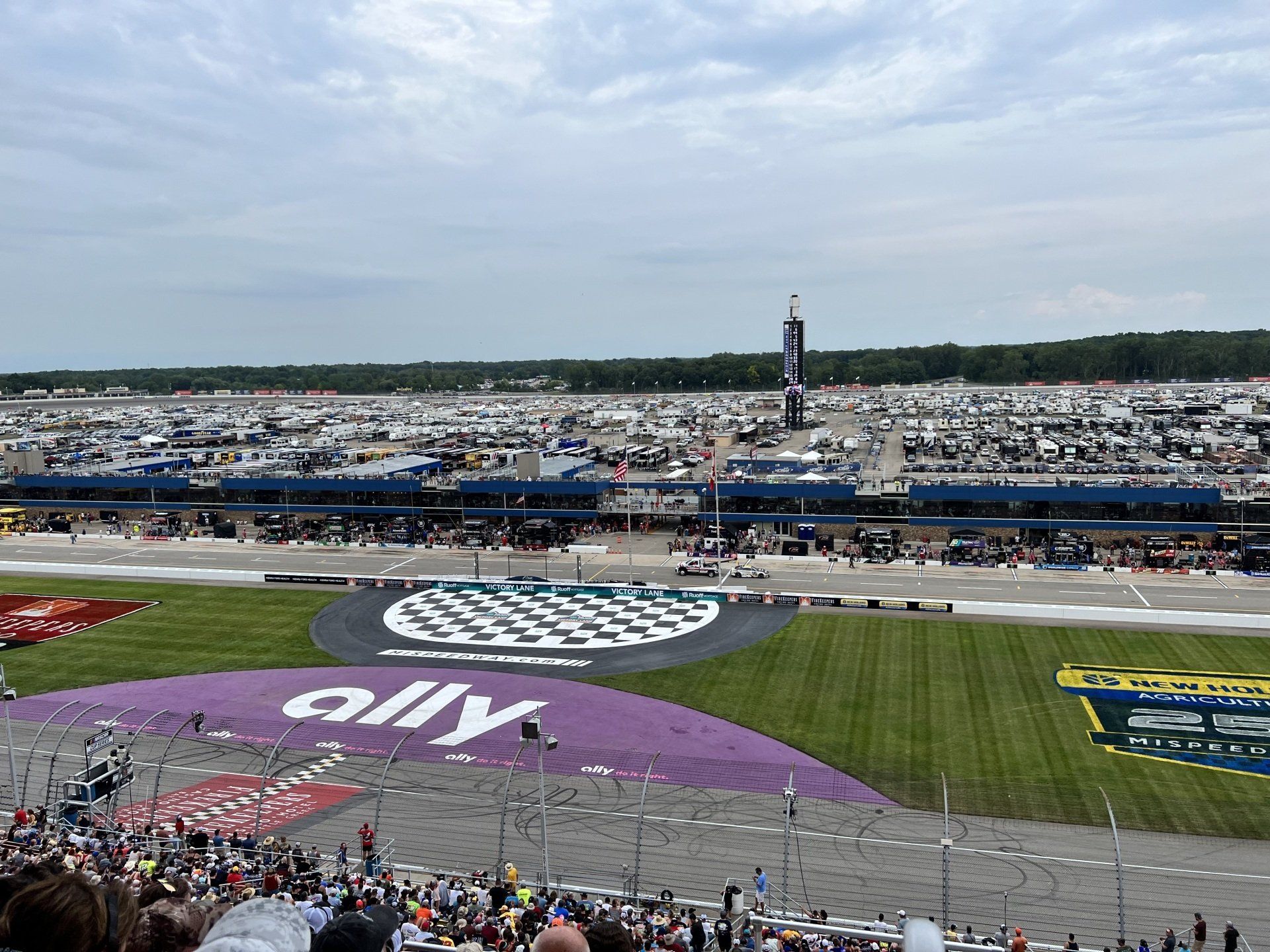 A crowd of people are watching a race at a race track.