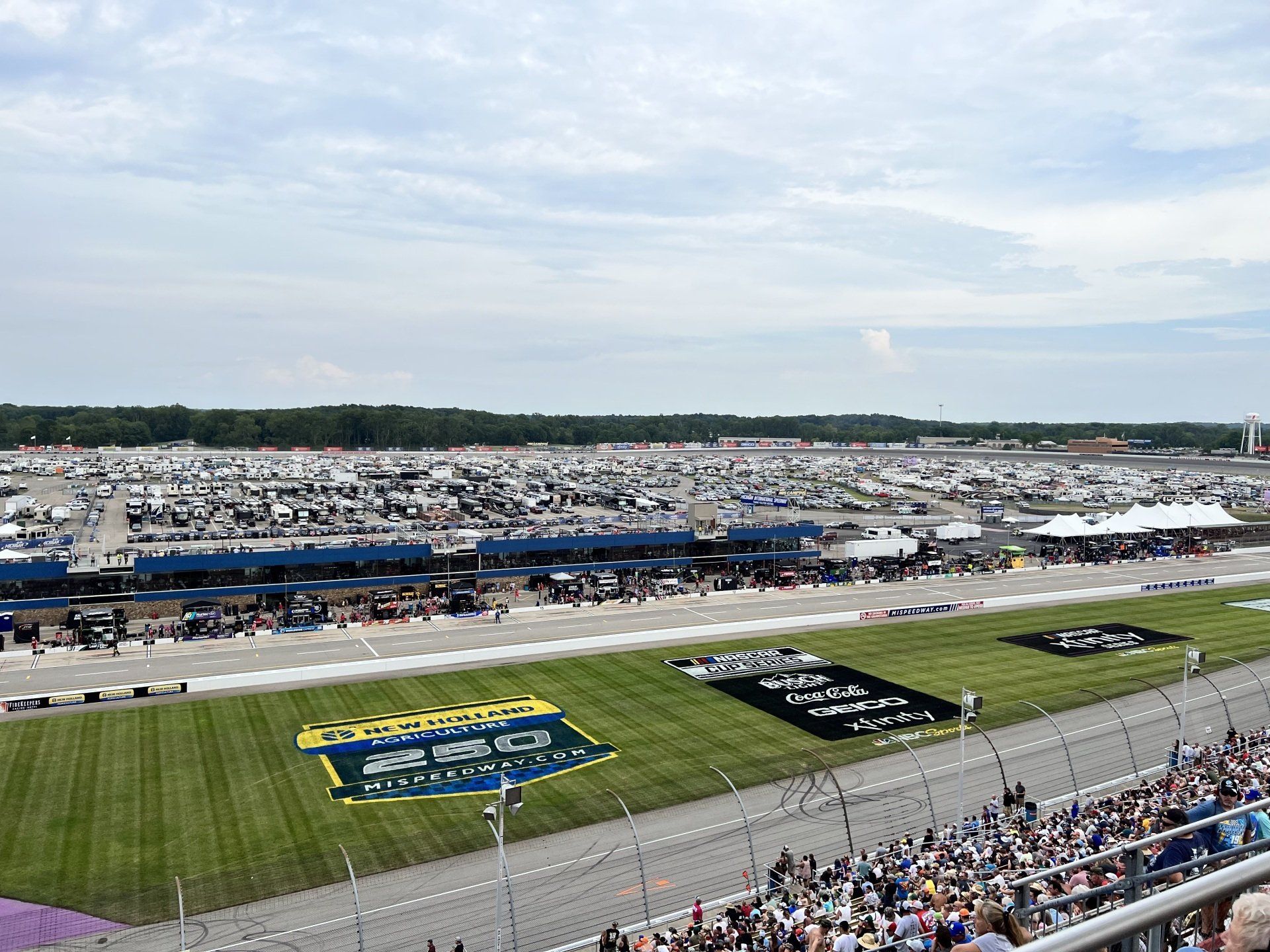 A crowd of people are watching a race at a race track.