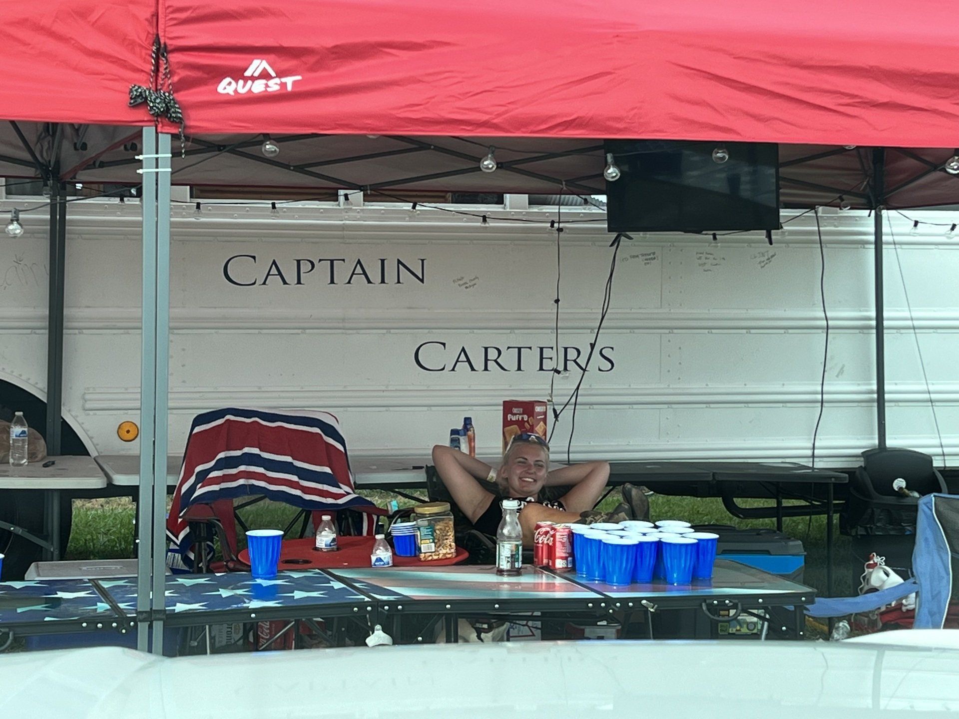 A man sits under a red tent that says captain carter 's