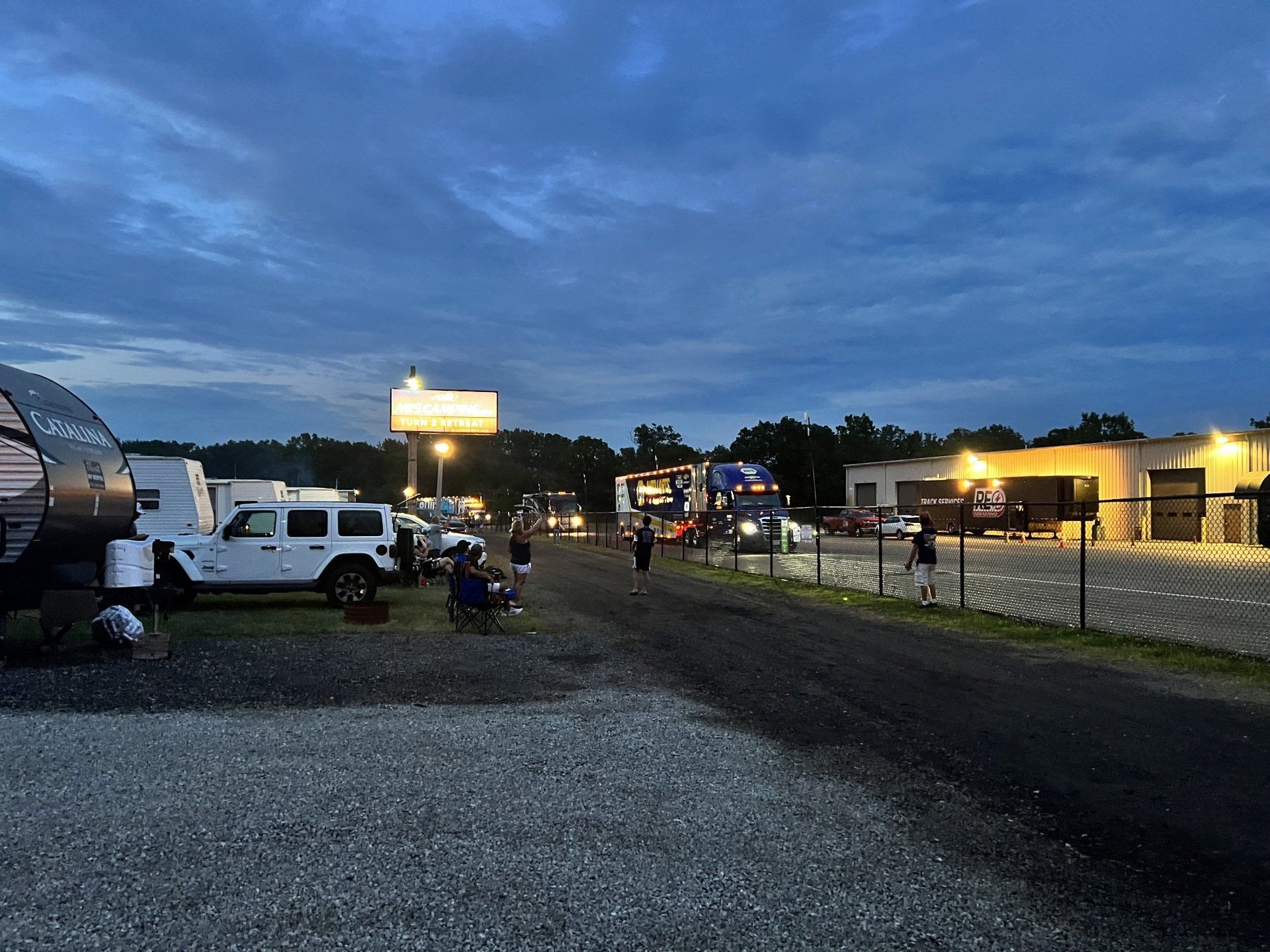 A group of people are standing in a parking lot next to a building.