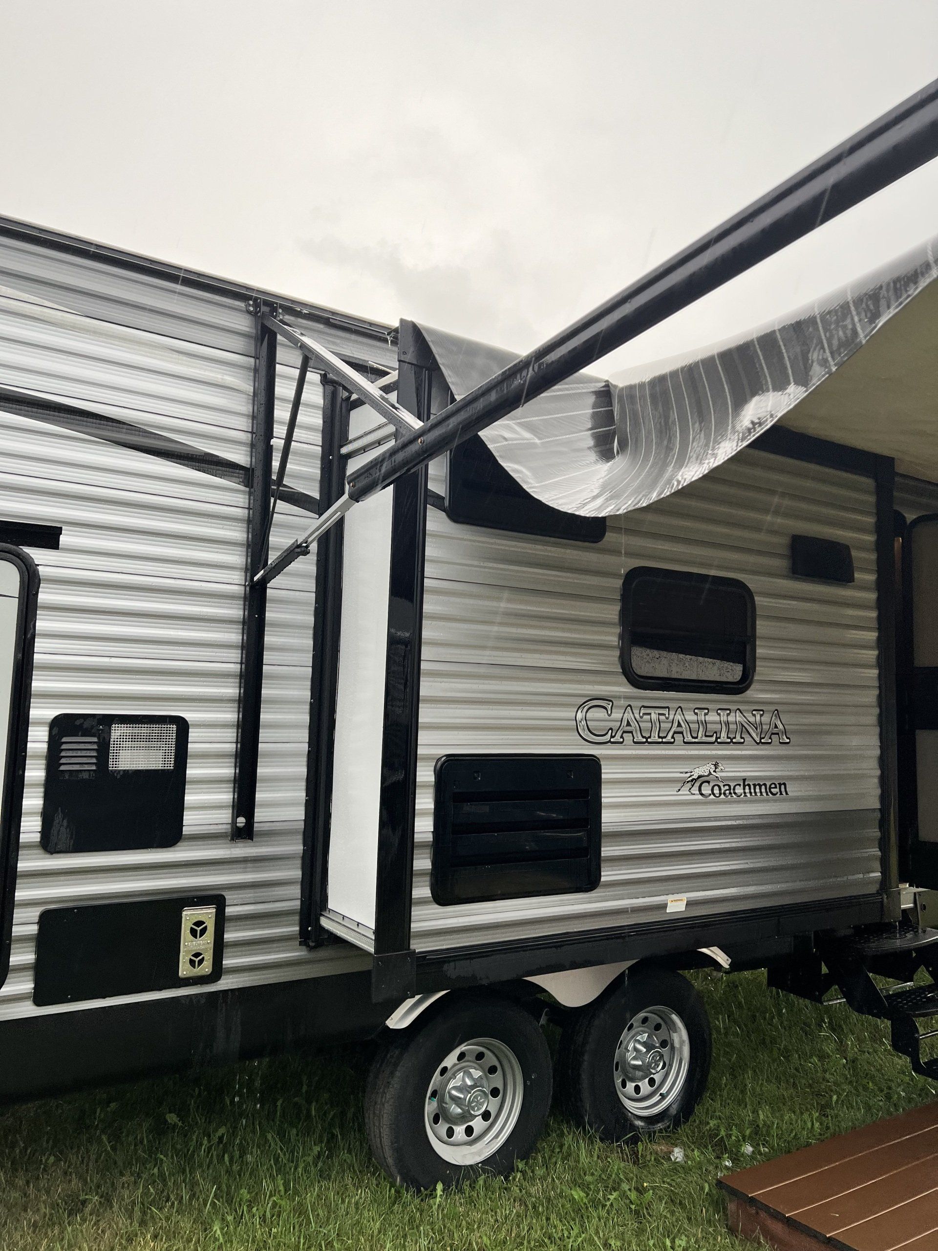 A silver trailer is parked in a grassy field.