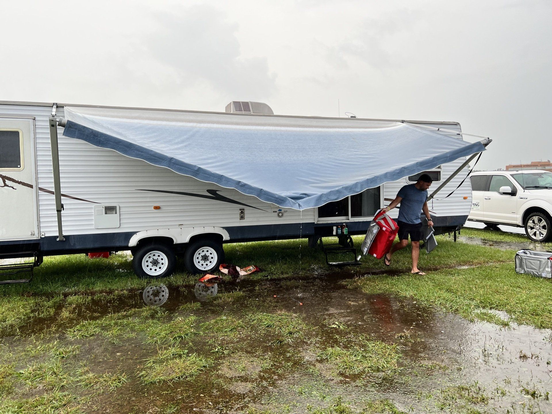 A man is standing in front of a trailer with an awning on it.