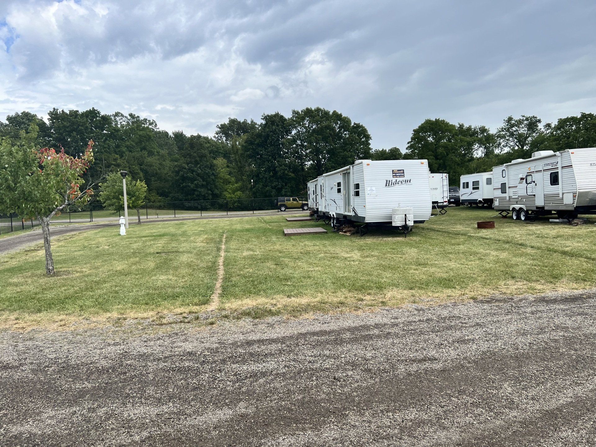 A row of trailers are parked in a grassy field.