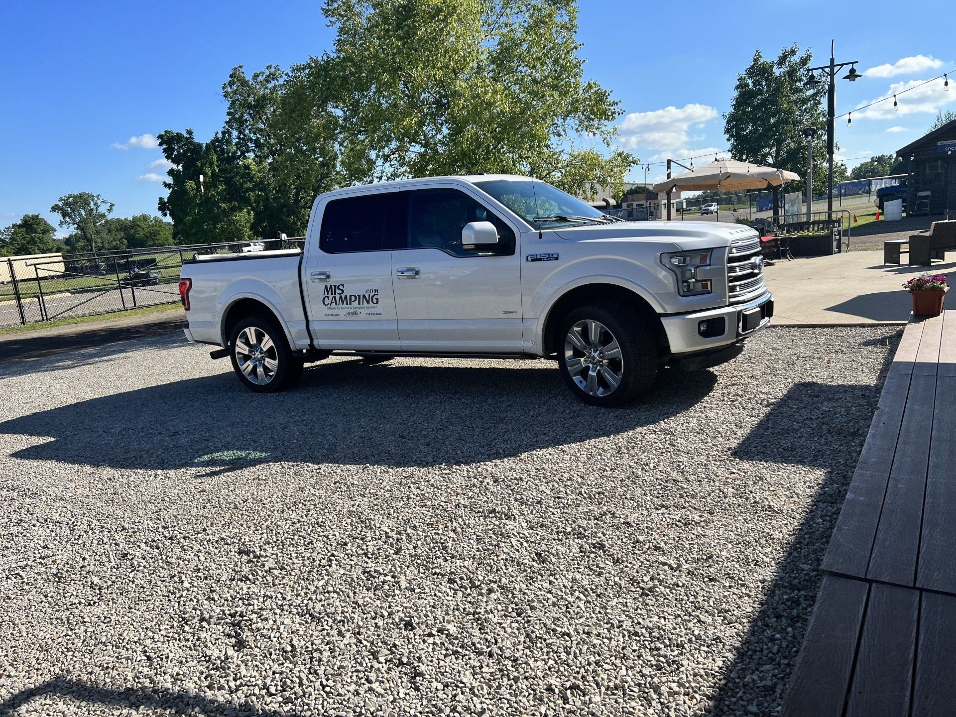 A white pickup truck is parked in a gravel lot.