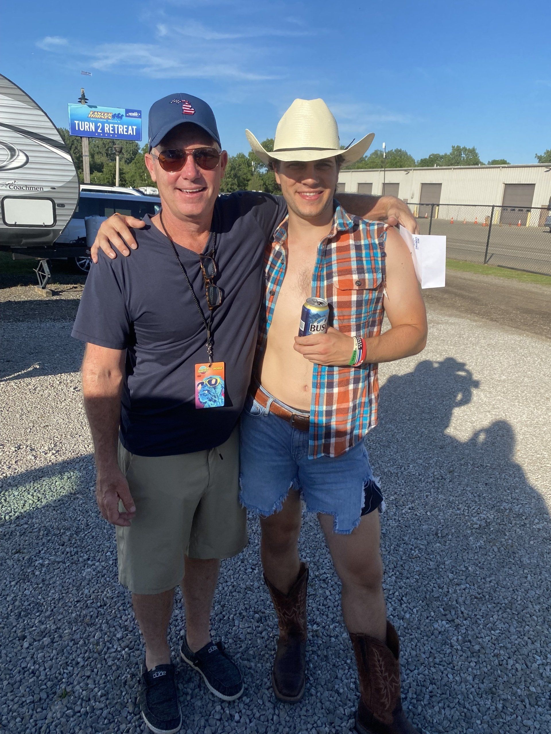 A man in a cowboy hat is standing next to another man in shorts.