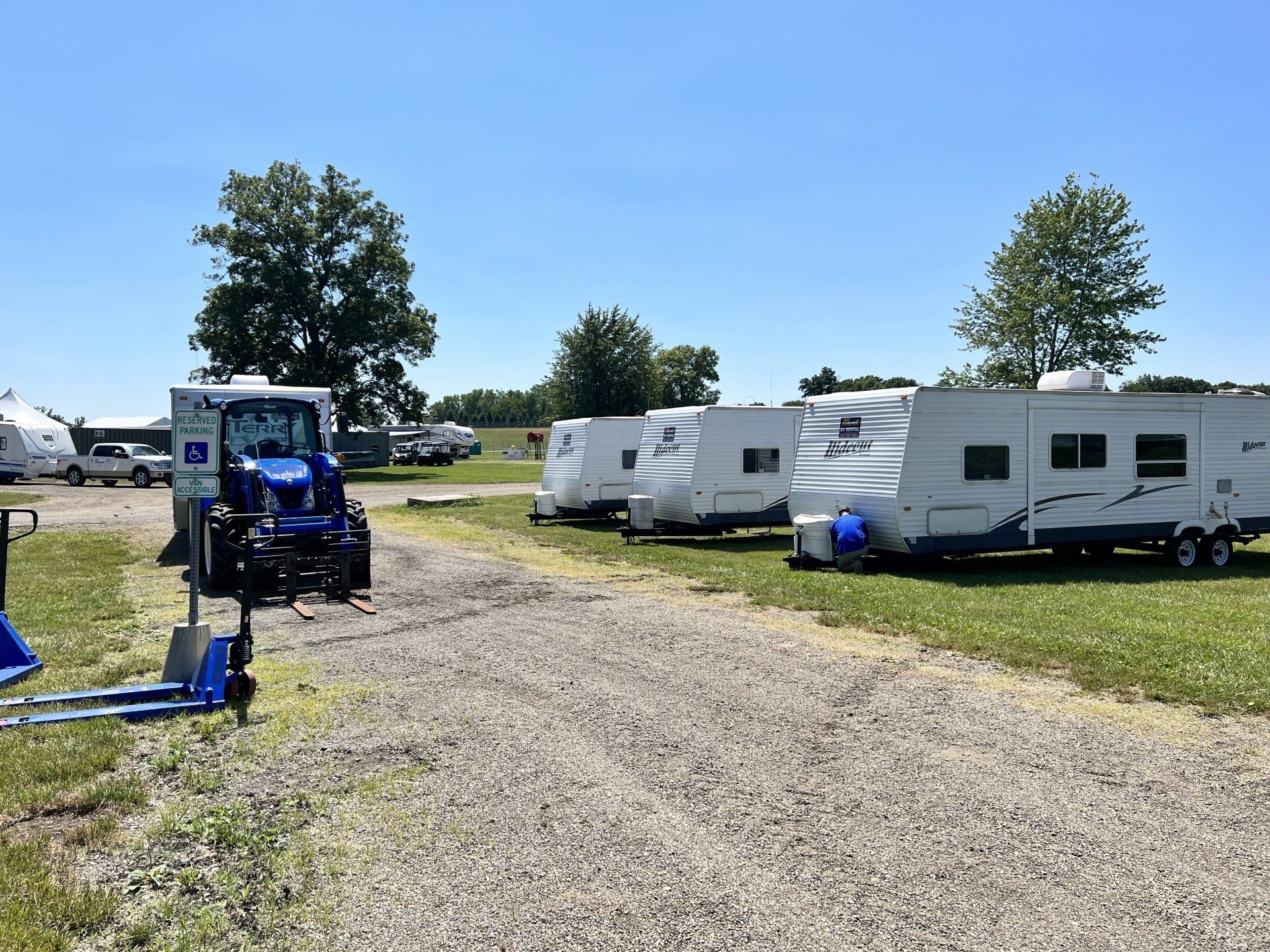 A row of rvs are parked in a gravel lot.