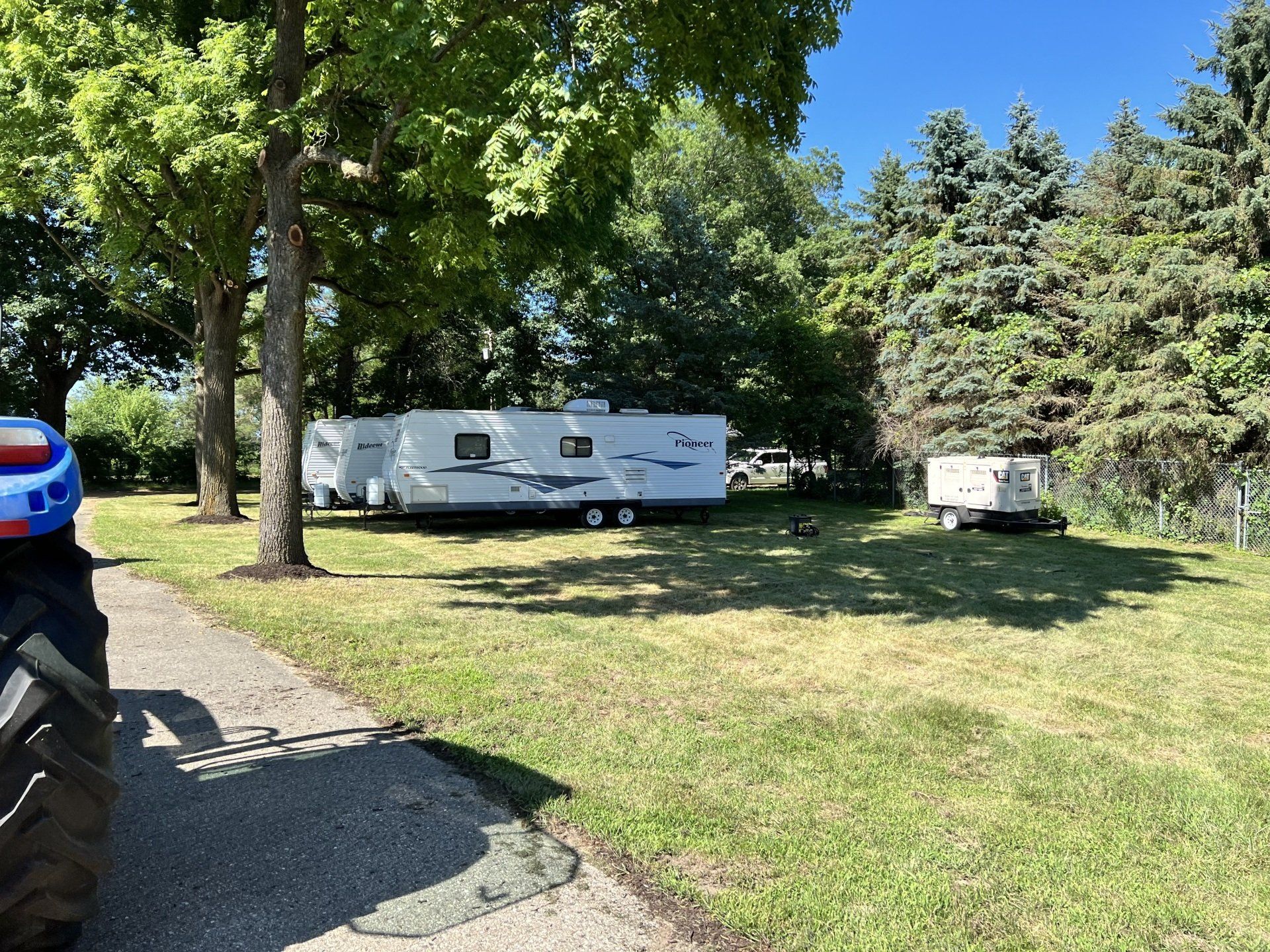 A rv is parked in a grassy field next to a road.