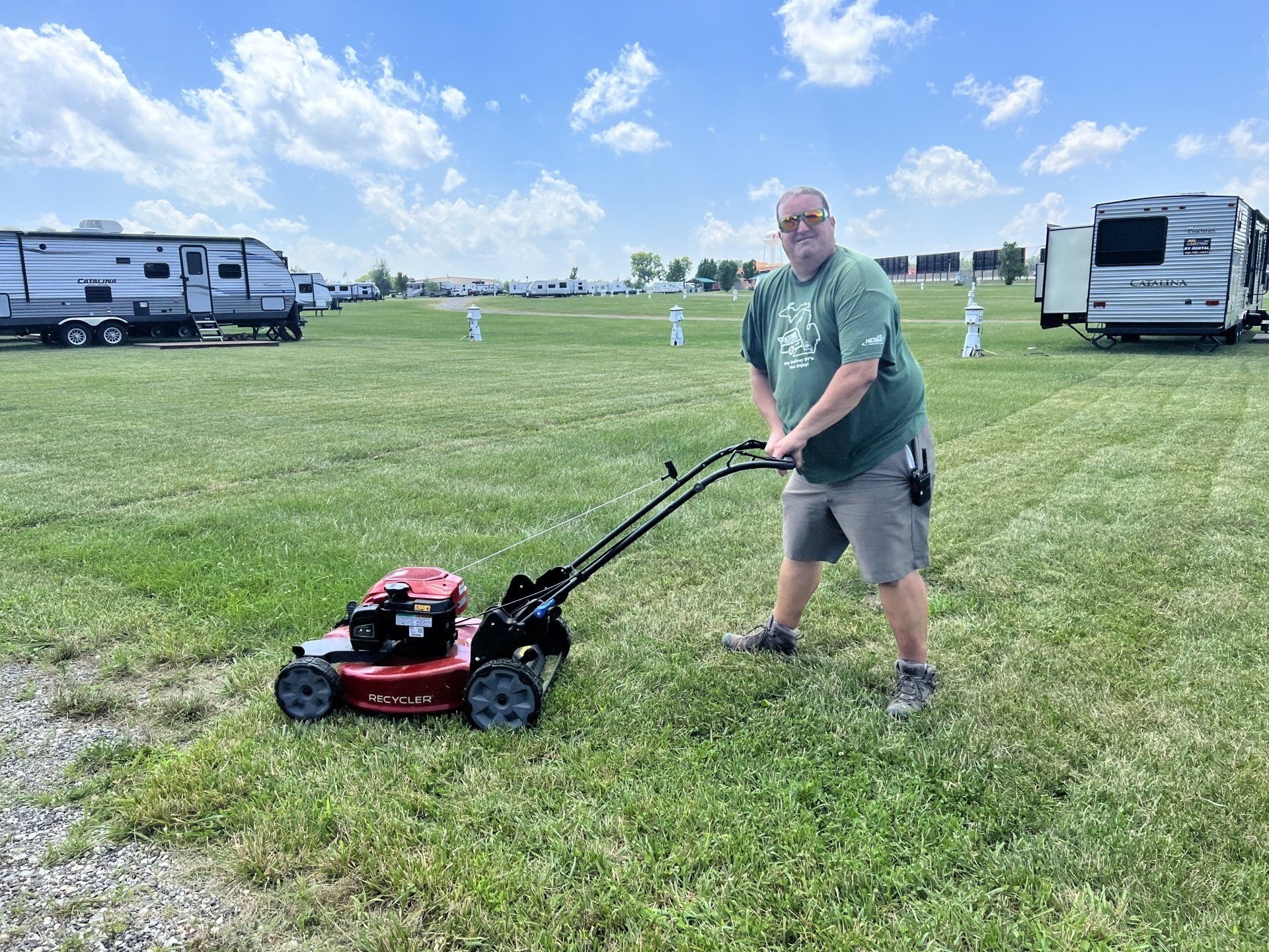 A man is standing next to a lawn mower in a field.