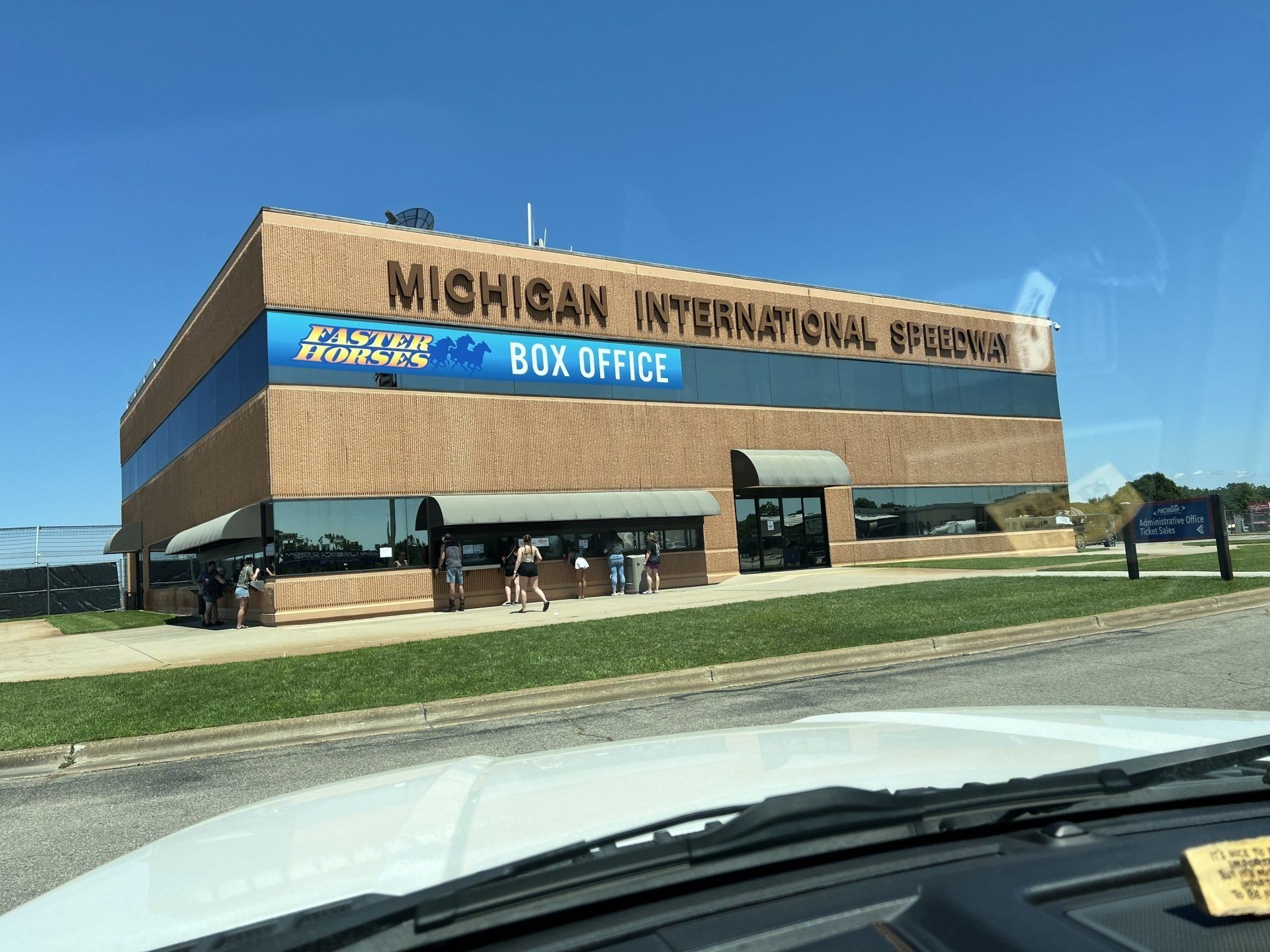 A view of a michigan international speedway box office from a car window.