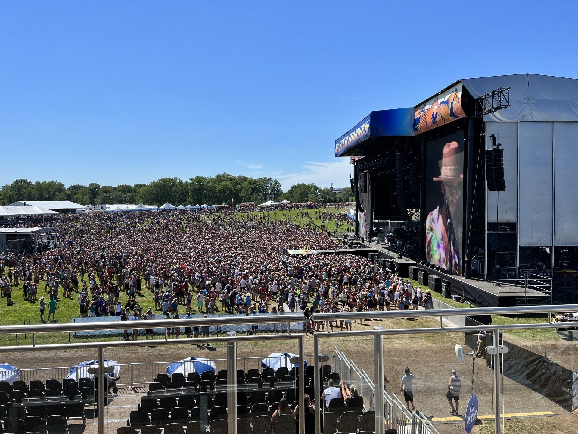 A large crowd of people are gathered in front of a stage at a concert.