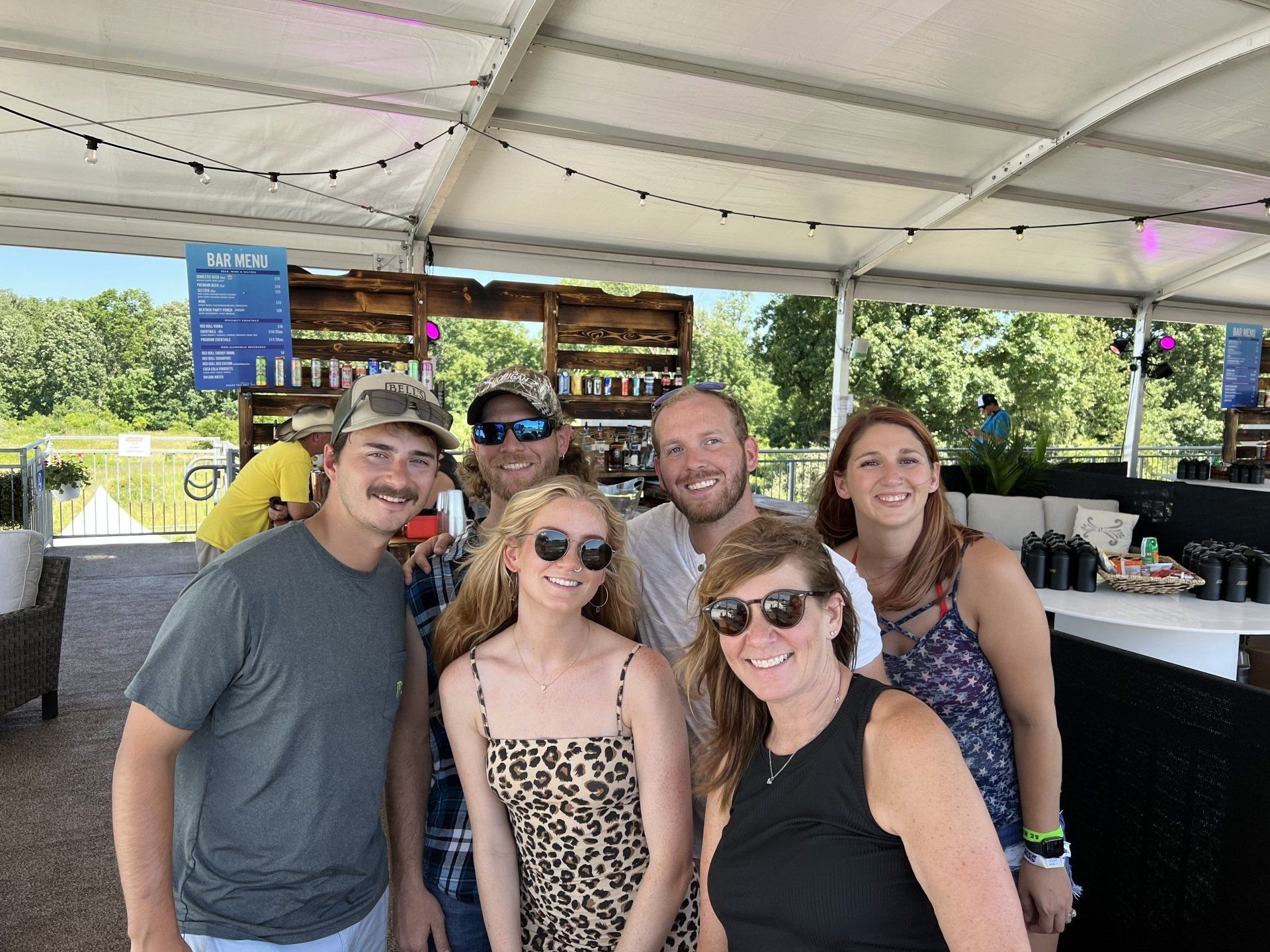 A group of people are posing for a picture under a tent.