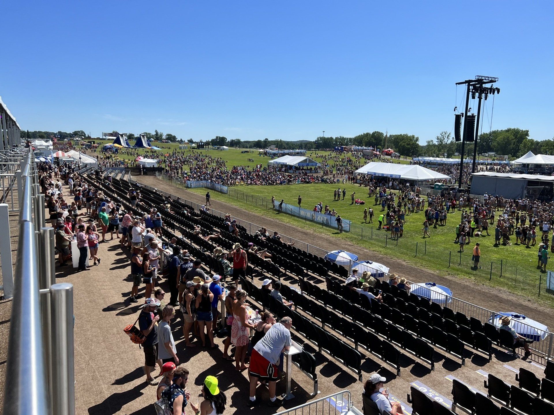 A large crowd of people are gathered in a field at a concert.