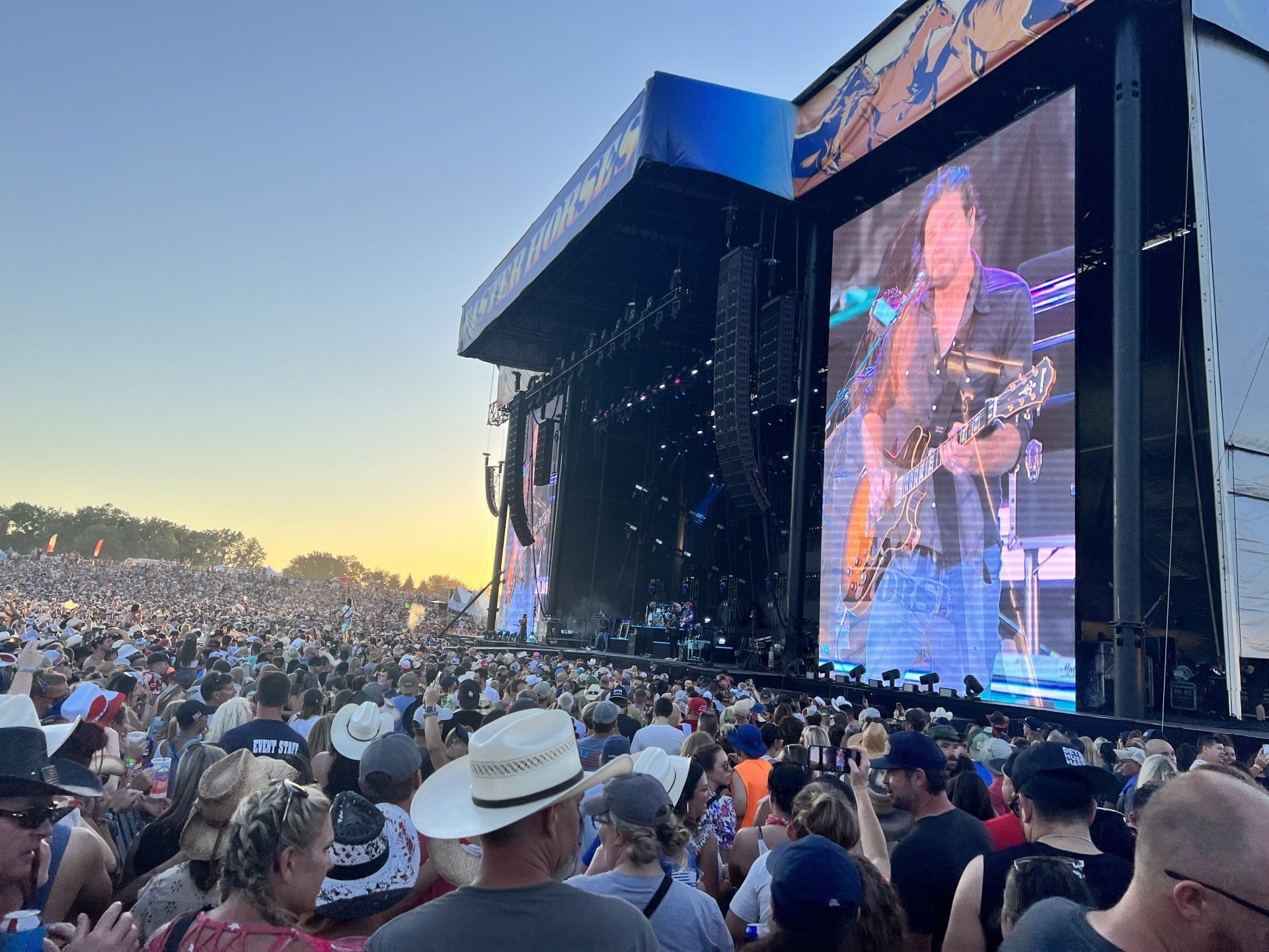 A crowd of people are watching a concert on a large screen.