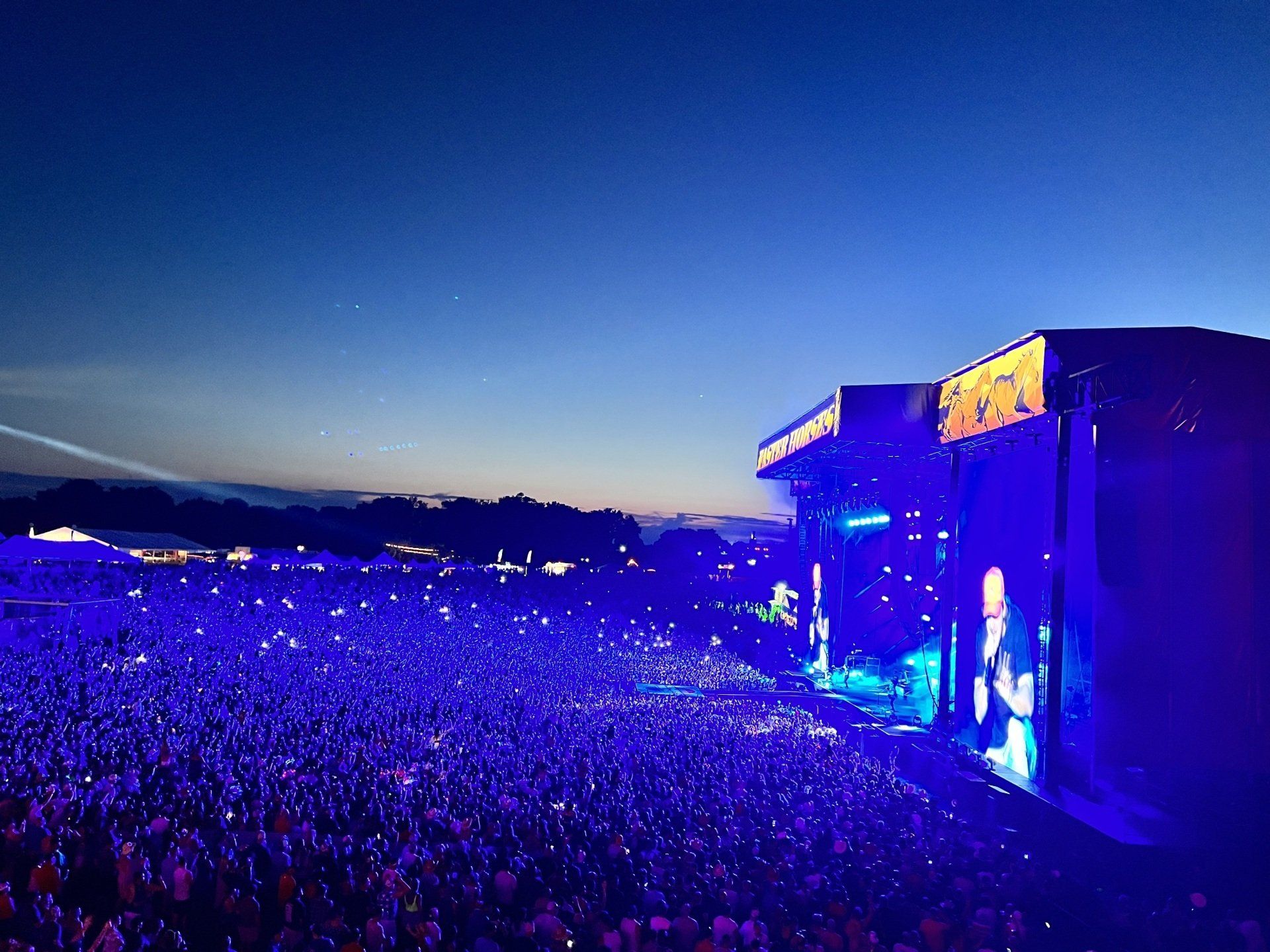 A crowd of people are gathered in front of a stage at a concert.