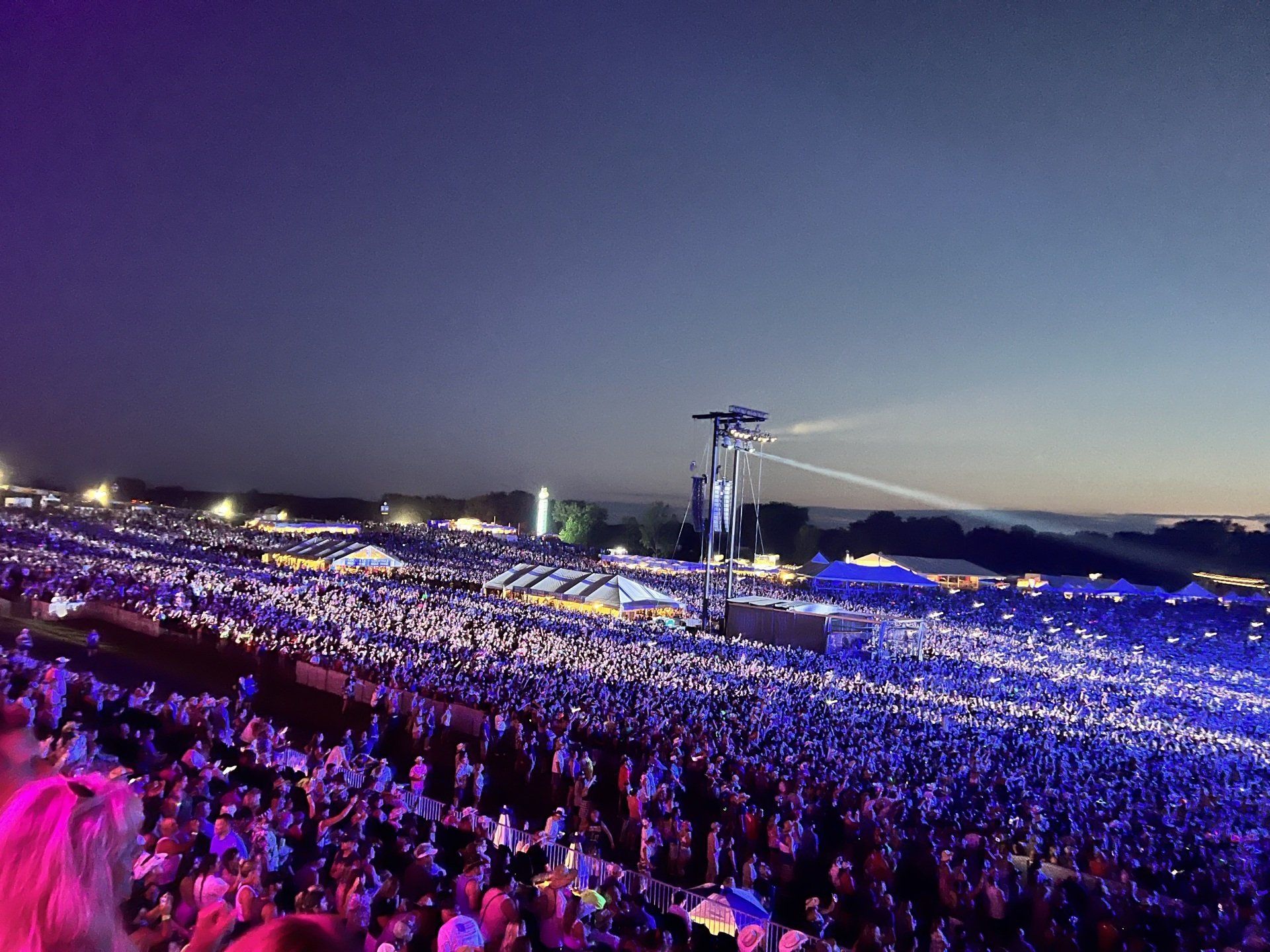 A large crowd of people are watching a concert at night.