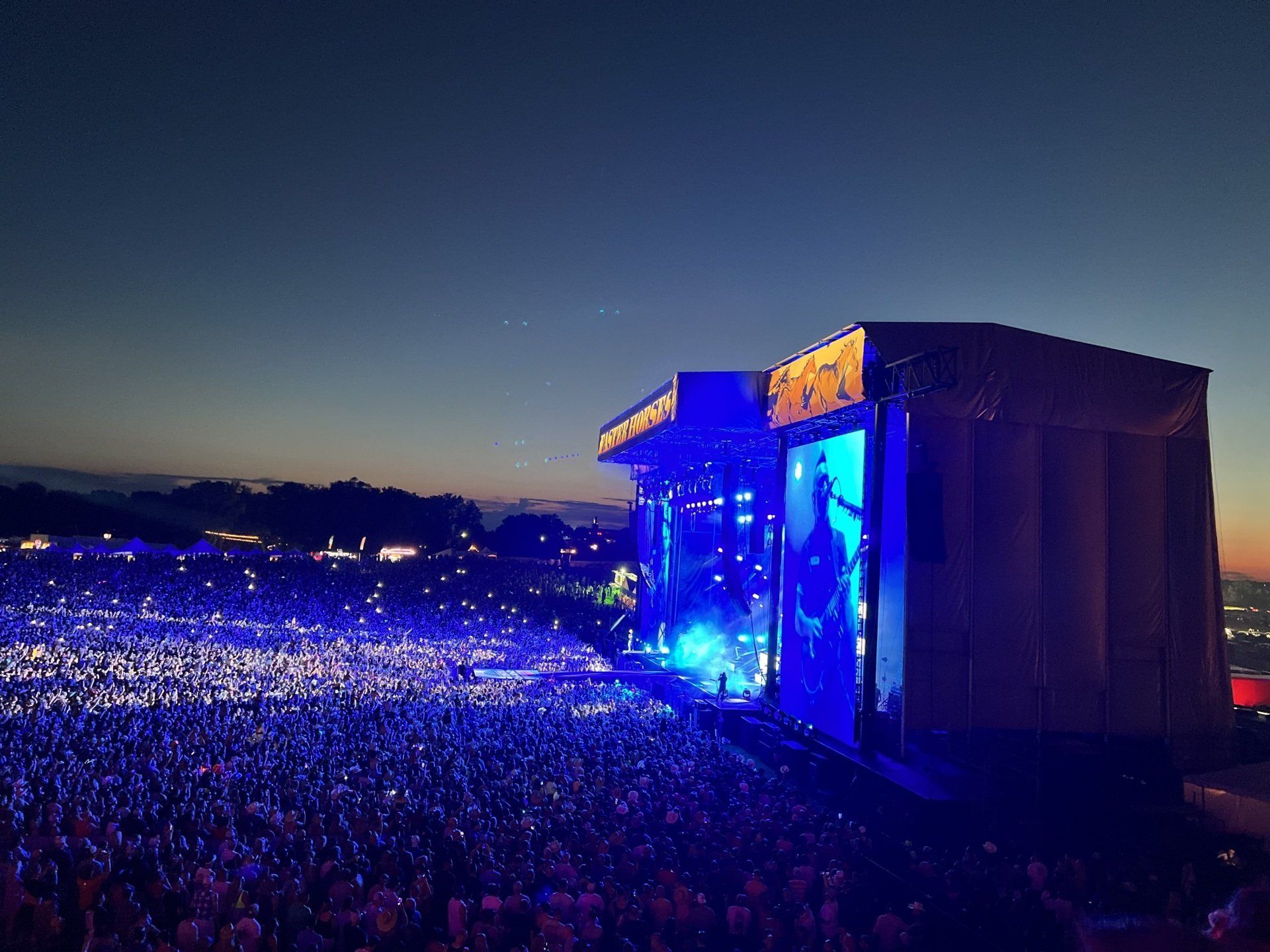 A large crowd of people are watching a concert at night