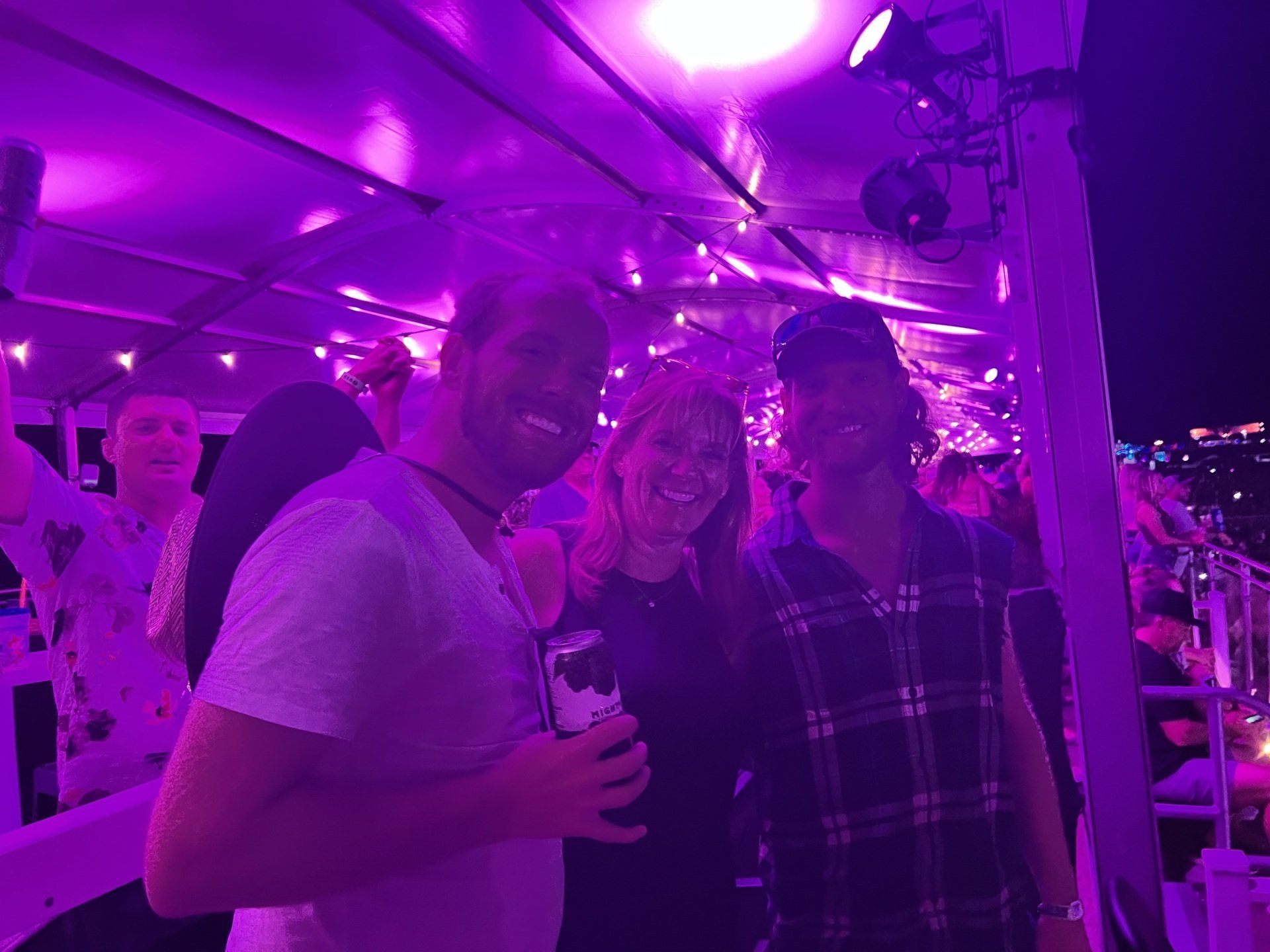 A group of people are posing for a picture at a party with purple lights.