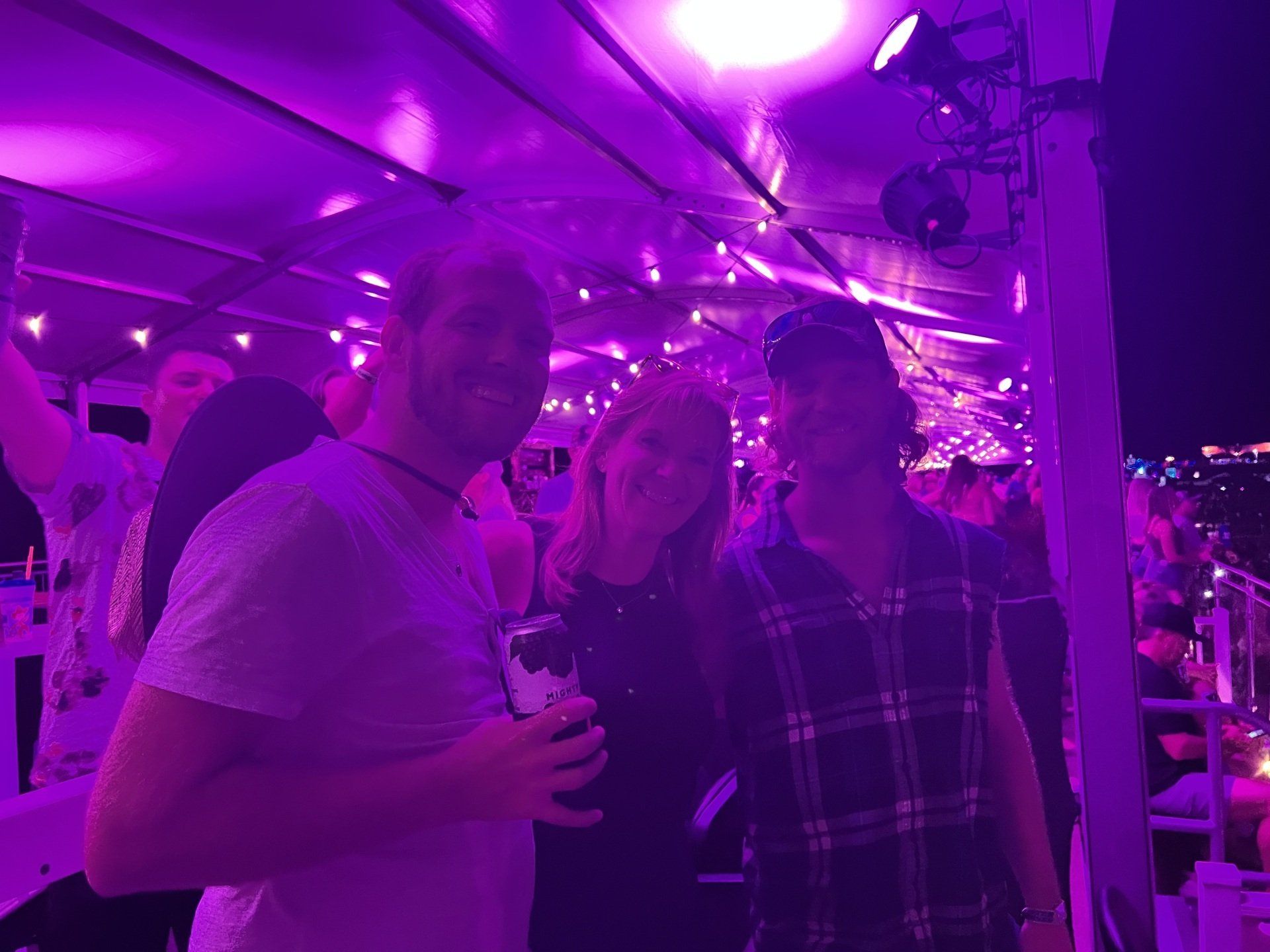 A group of people are standing in a room with purple lights.