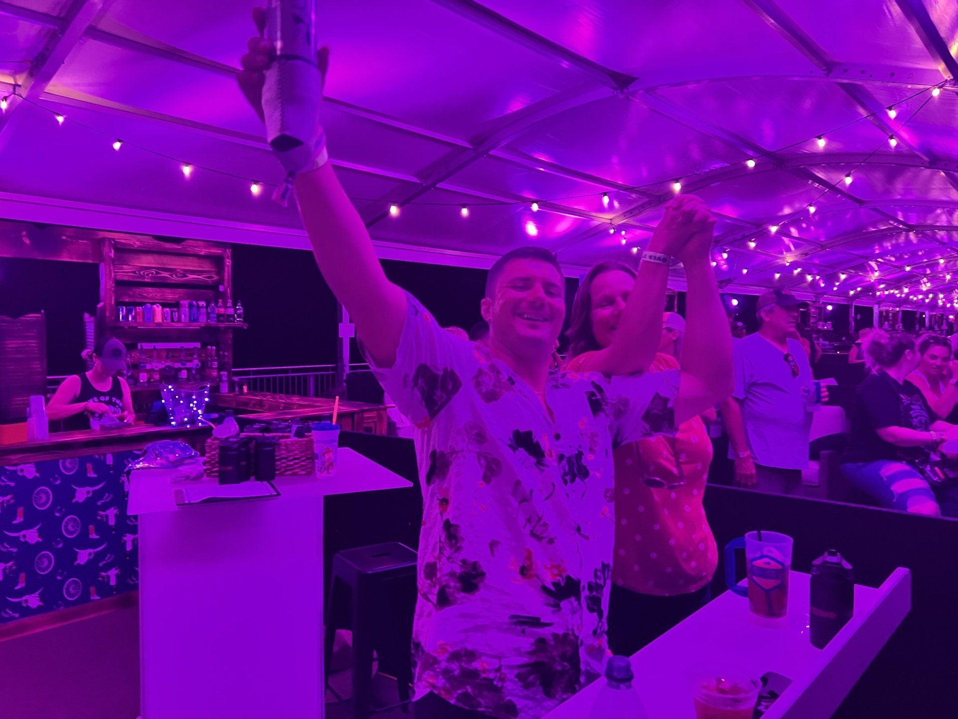 A man and a woman are standing in a room with purple lights.