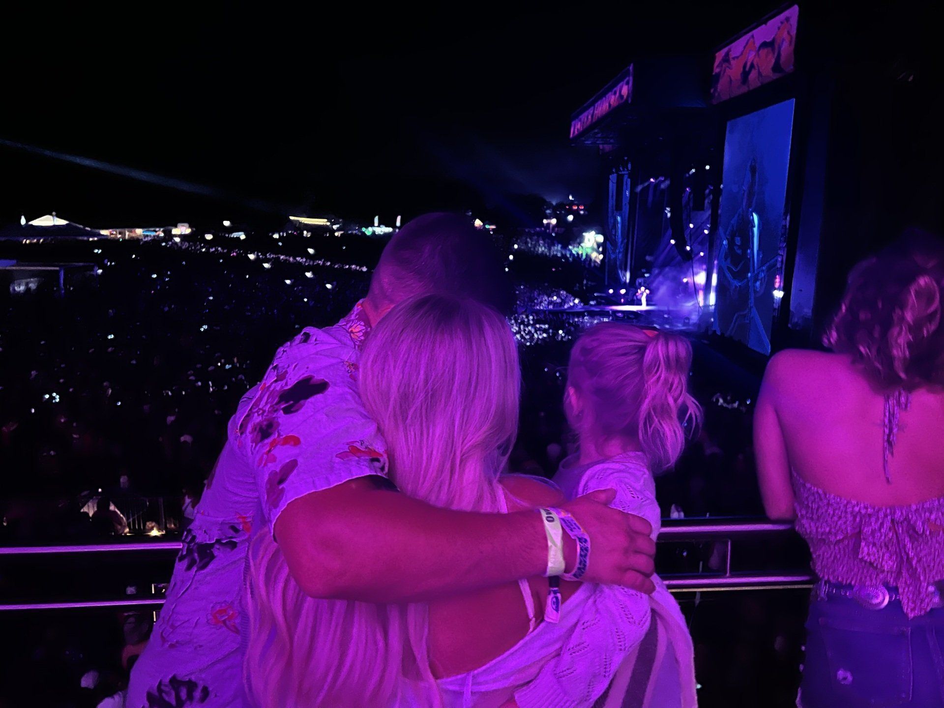 A man and a woman are hugging in front of a crowd at a concert.