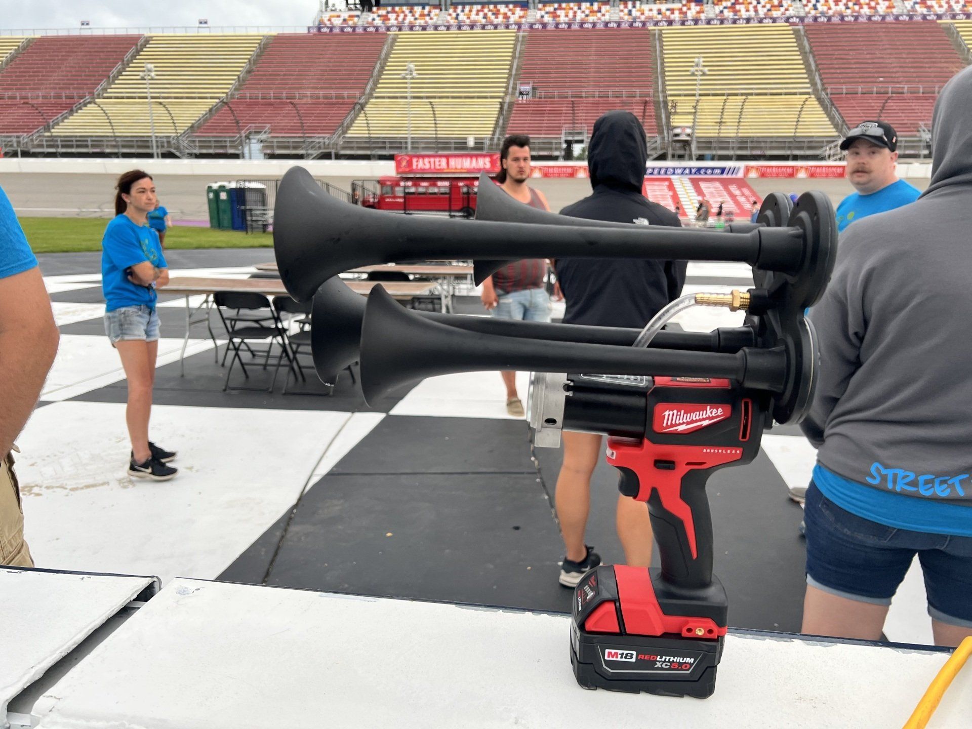 A group of people are standing in front of a stadium holding horns.
