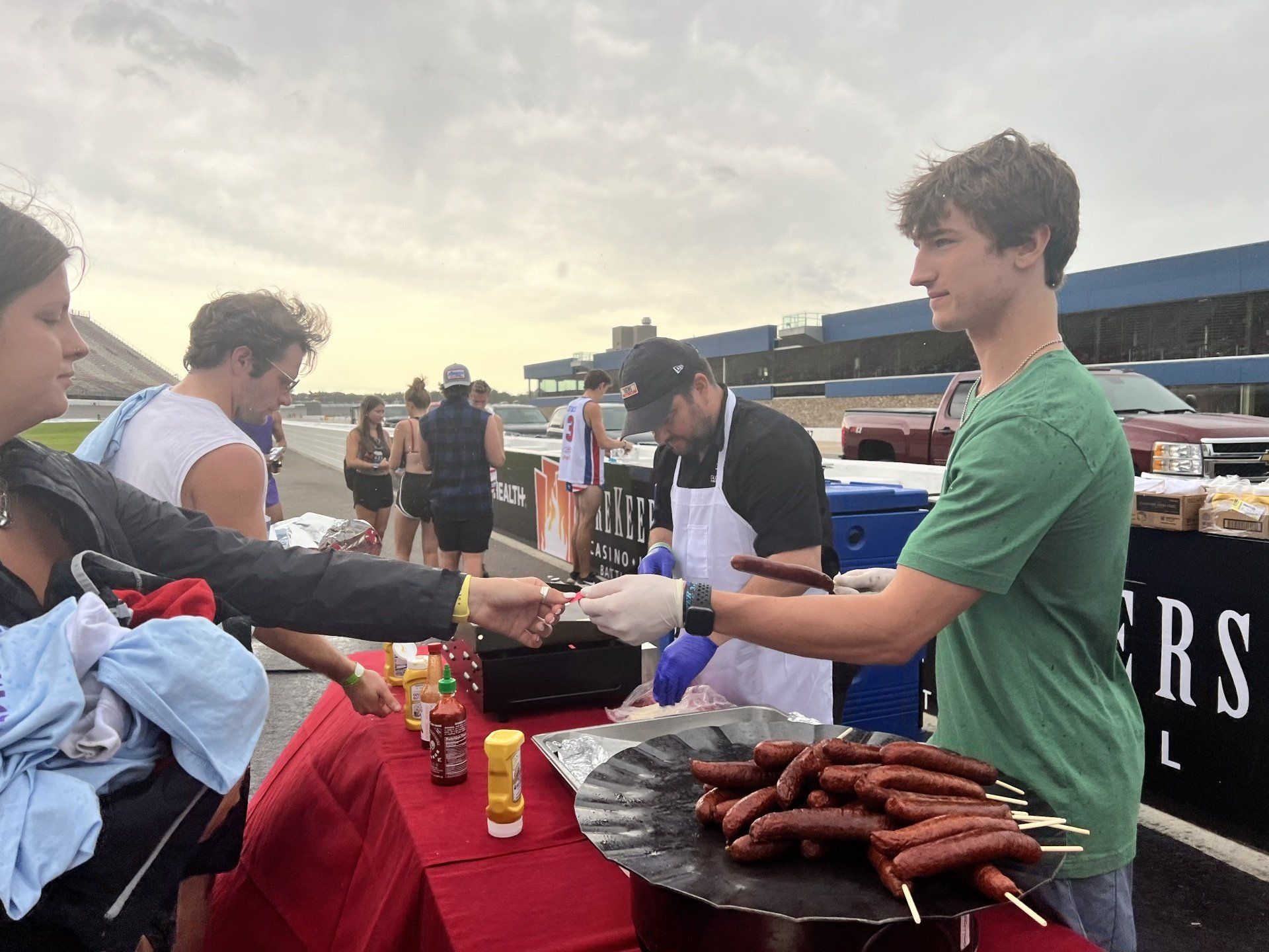 A man is serving hot dogs to a woman at a table.