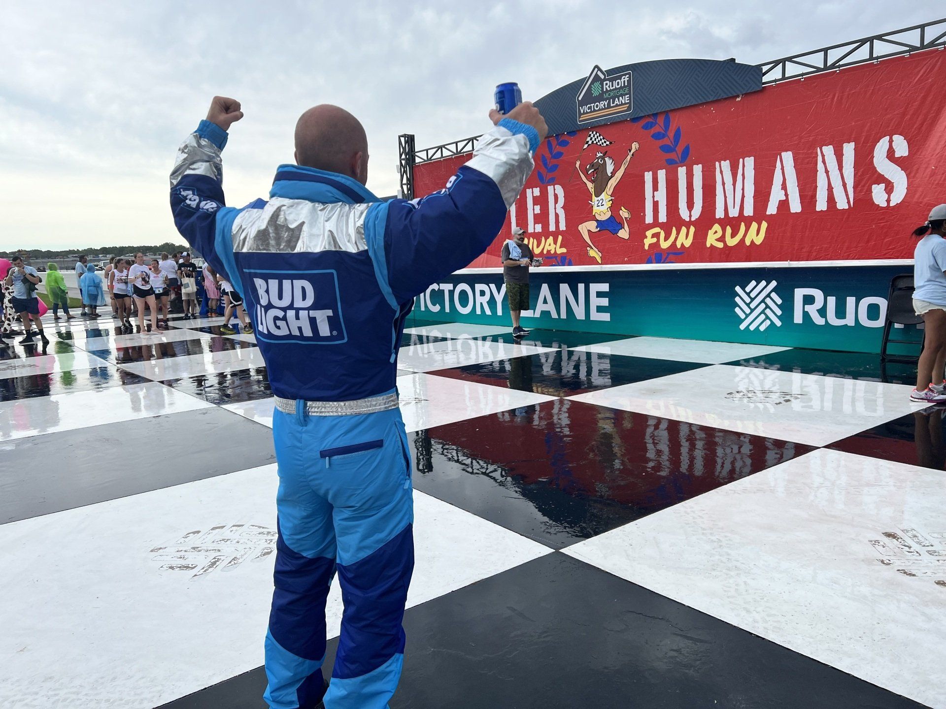 A man in a blue suit is standing in front of a sign that says humans