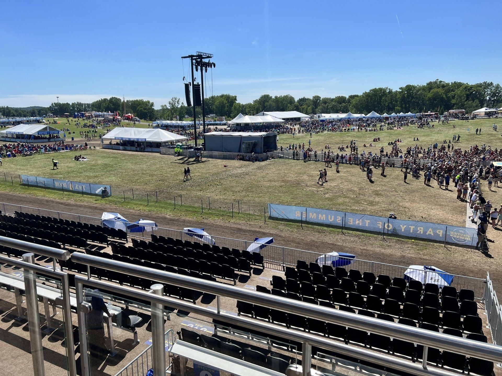 A large crowd of people are gathered in a field at a music festival.