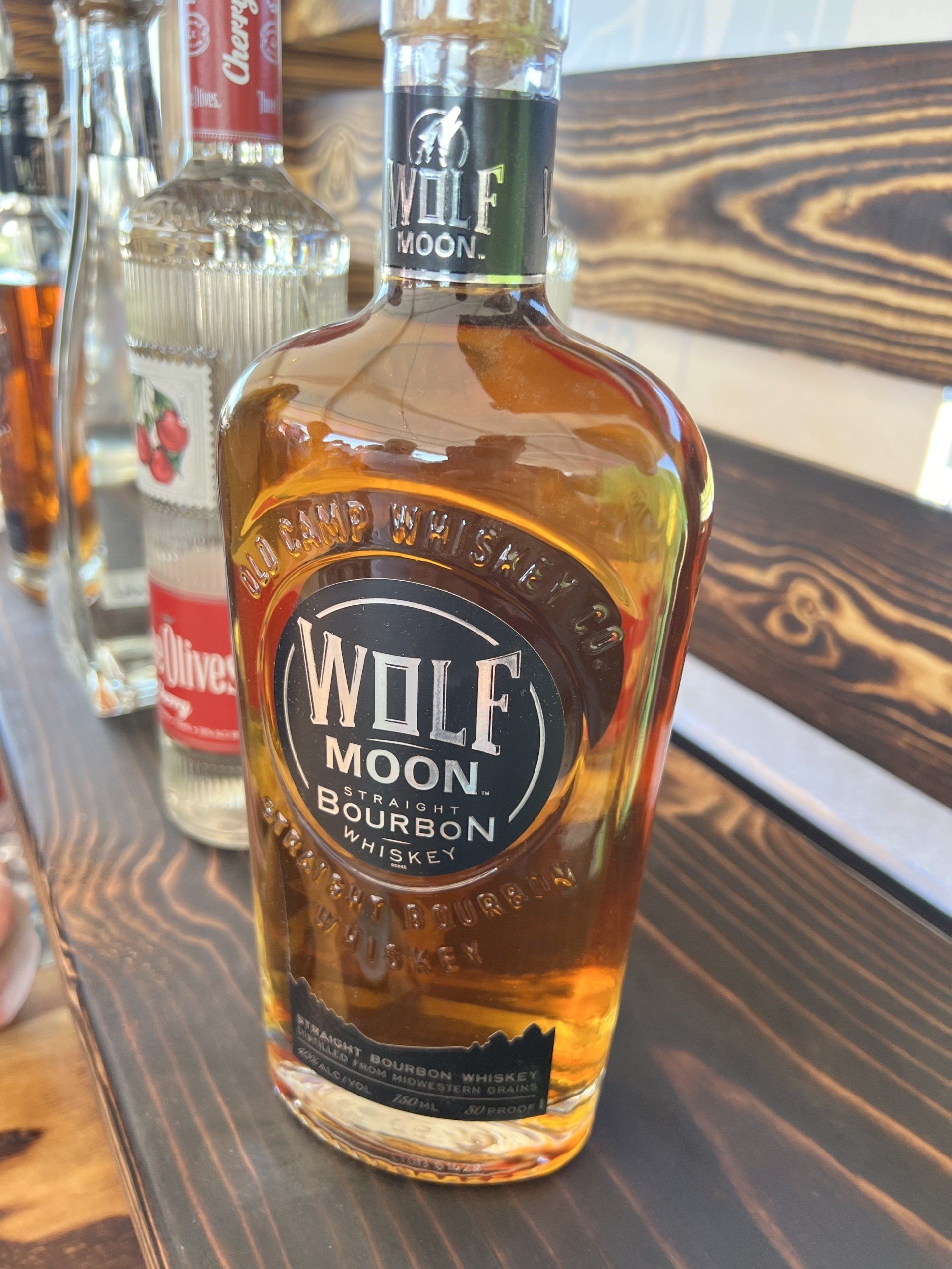 A bottle of wolf moon bourbon sits on a wooden shelf