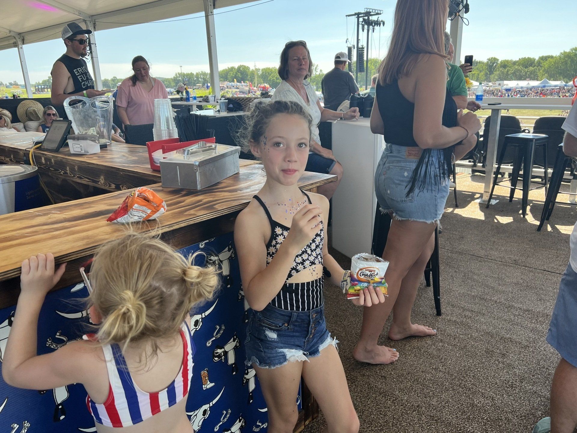 Two little girls are standing in front of a bar.