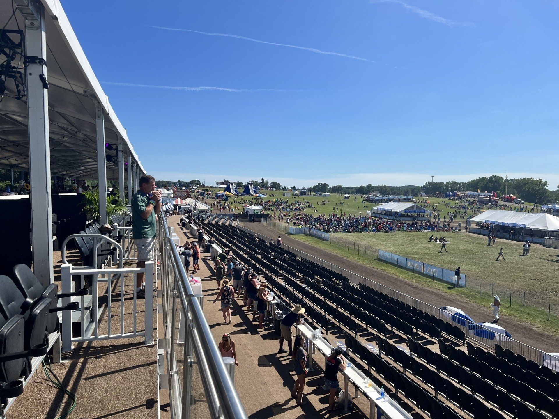 A man is standing on a balcony overlooking a race track.