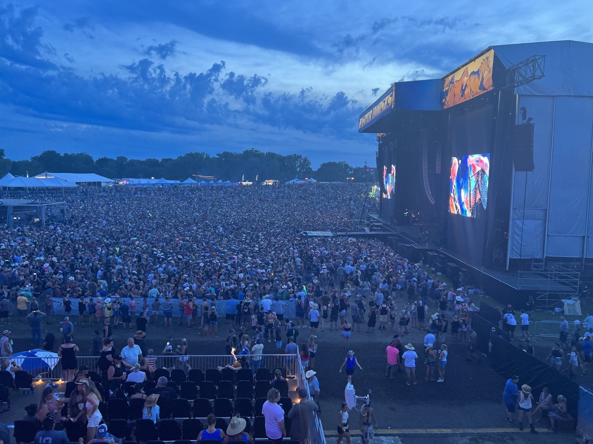 A crowd of people are standing in front of a stage at a concert.