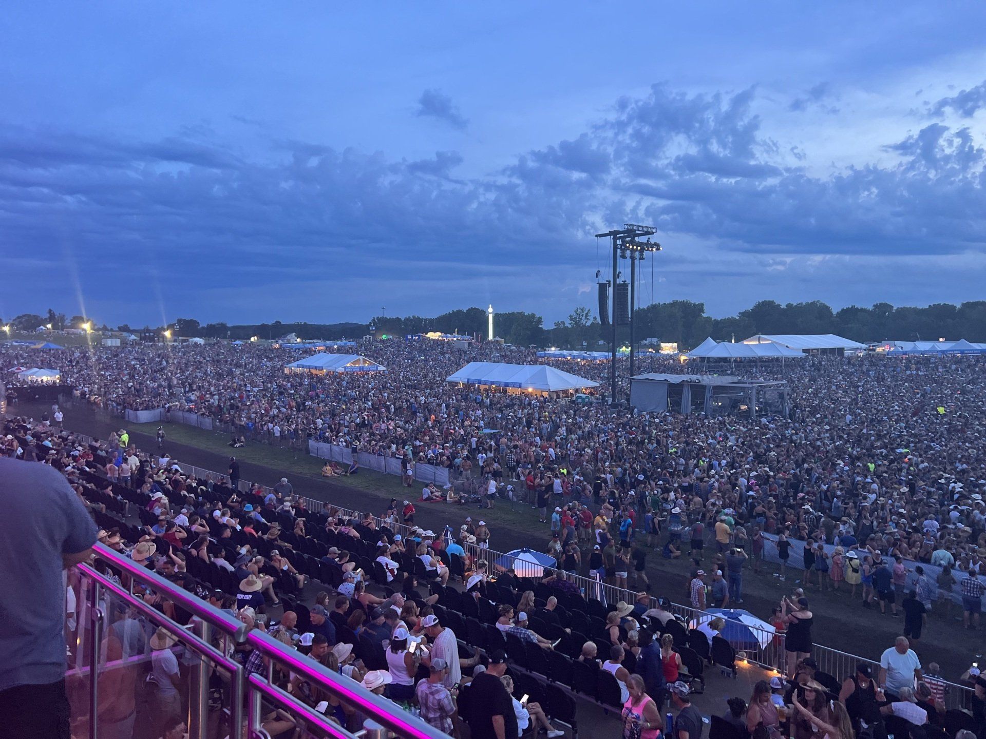 A large crowd of people are sitting in a stadium at a concert.