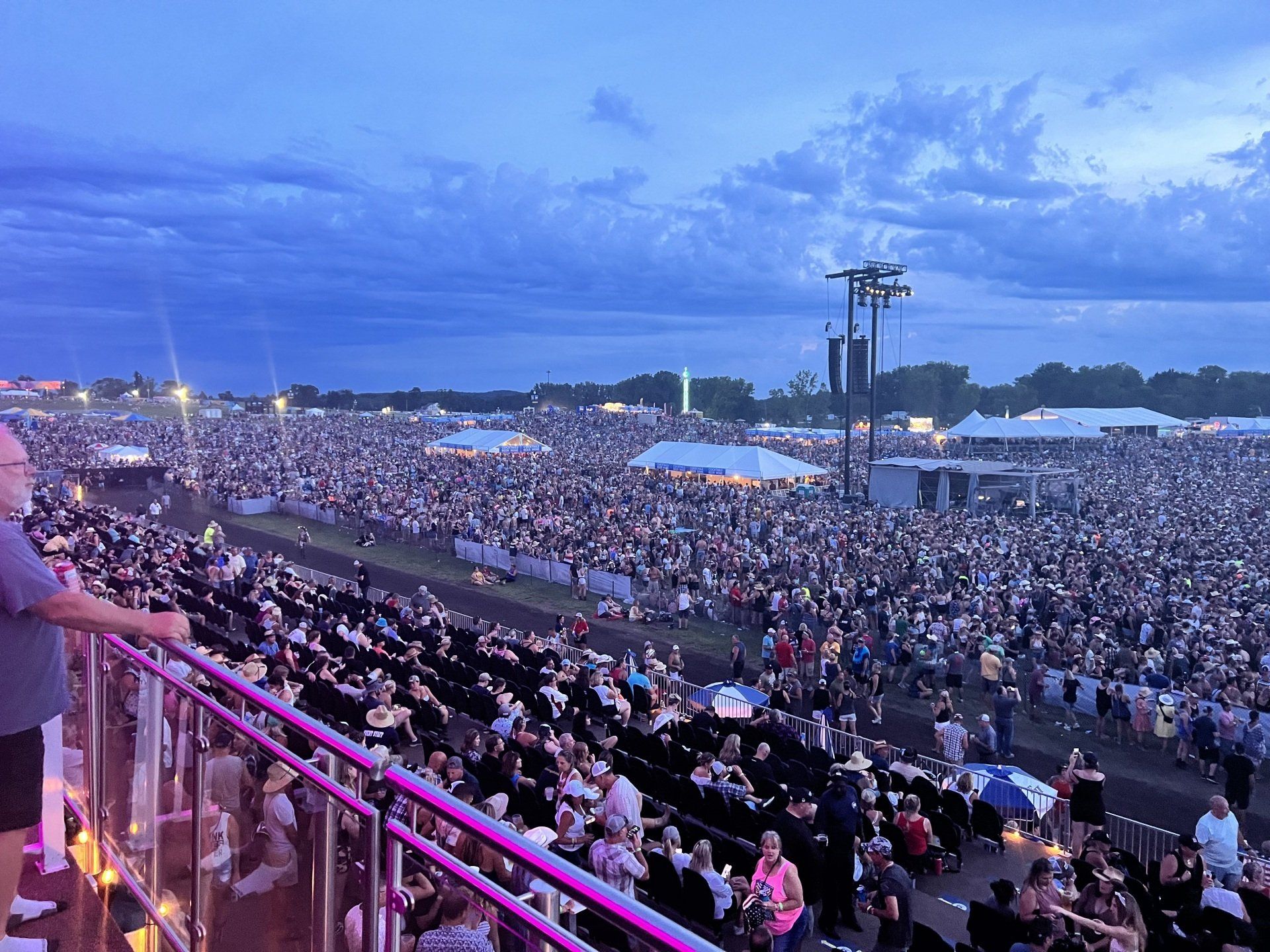 A man is standing on a balcony overlooking a crowd of people at a concert.