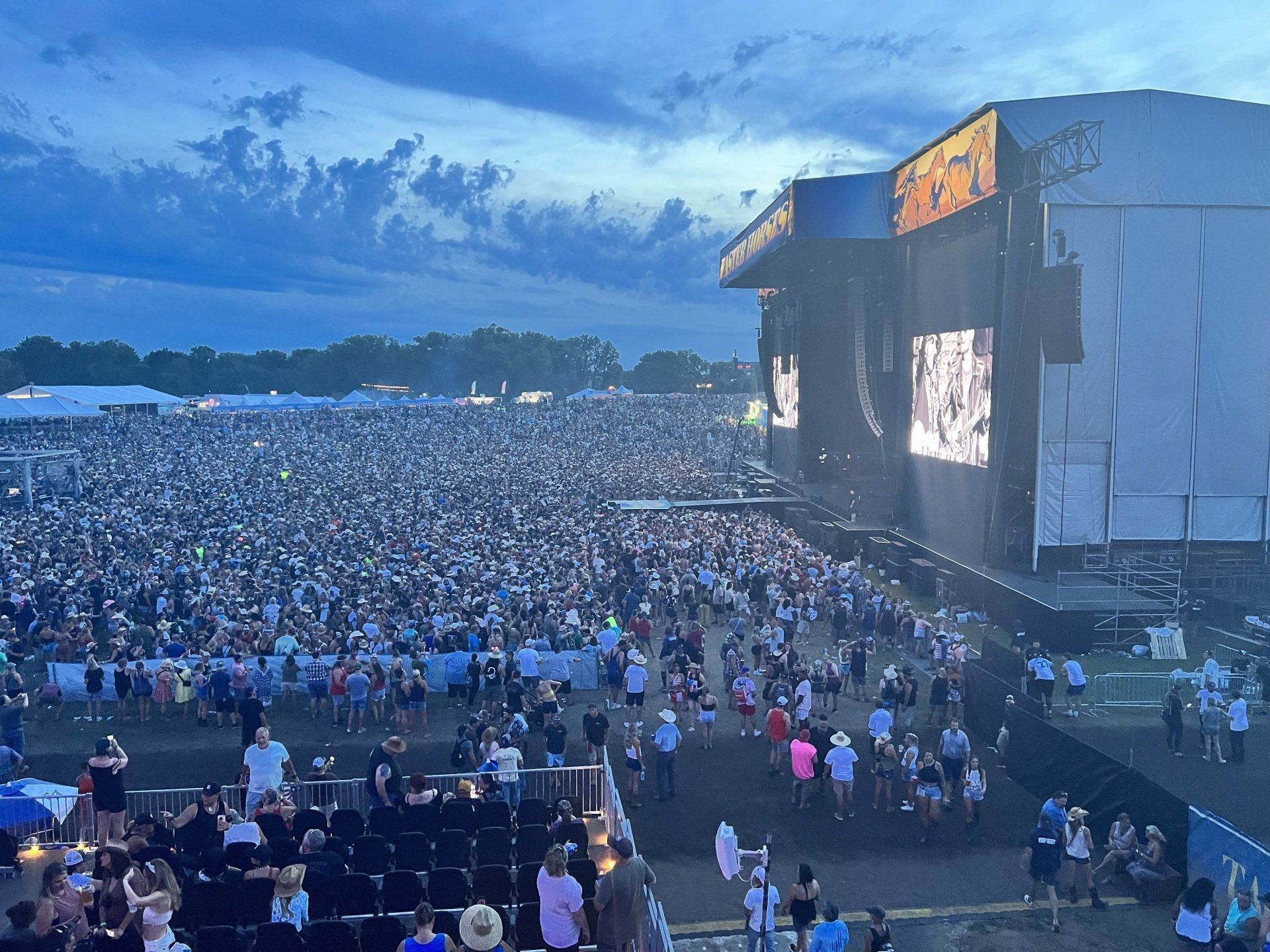 A large crowd of people are watching a concert at a music festival.
